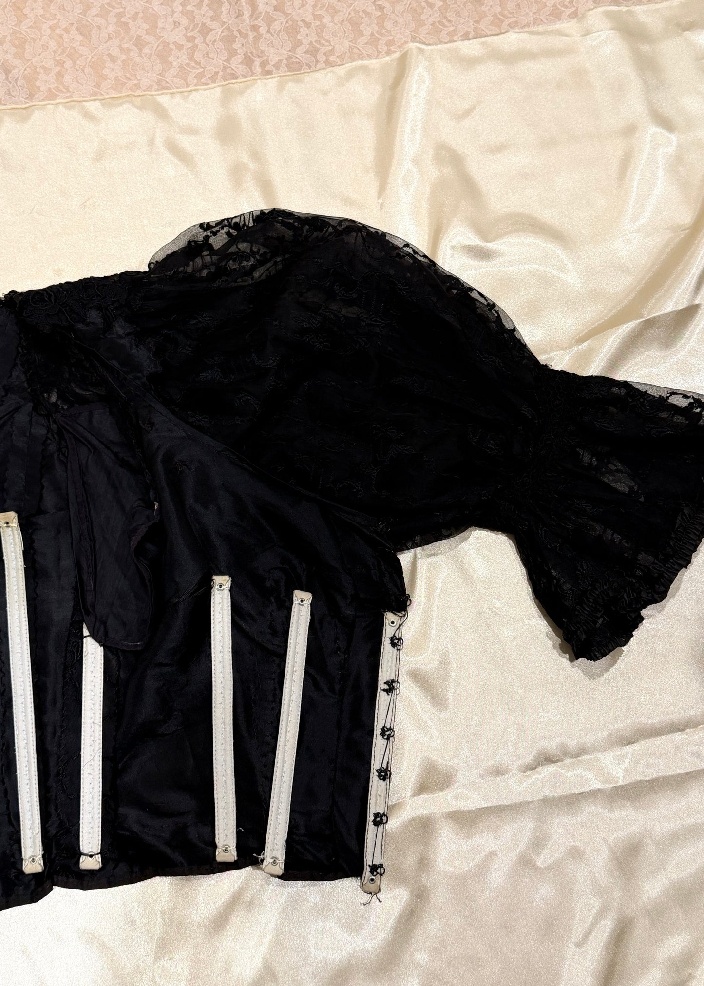 1890's Victorian mourning corset Black lace garment on a mannequin with a plain background