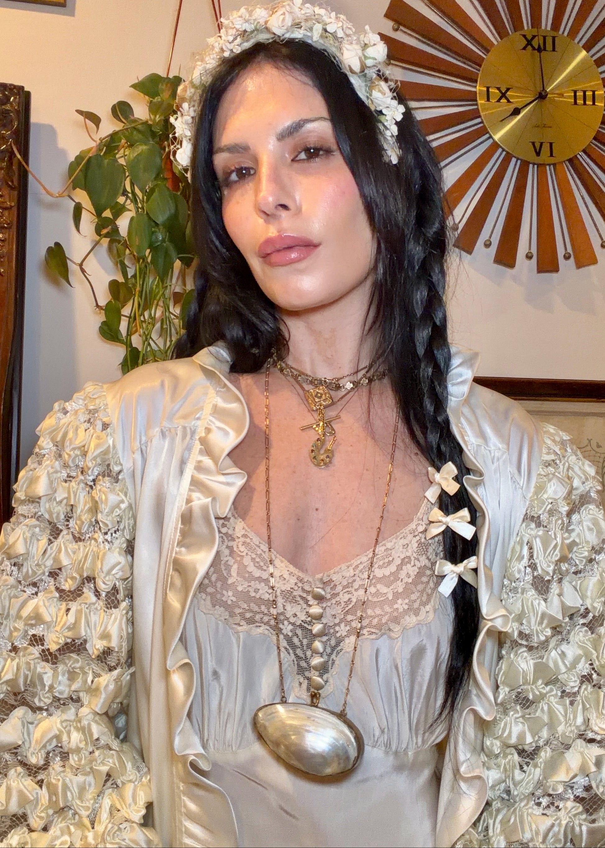Woman in a white 1930s bias cut dress standing in a room with decorative elements.