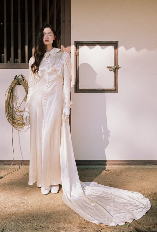 Down the center of the bodice is a hidden keyhole opening, sitting between the inverted V shaped empire waistline. The front side is topped with 52 decorative buttons vertically descending from the bust to the hem, adding a unique element to this elegant ensemble.&nbsp;