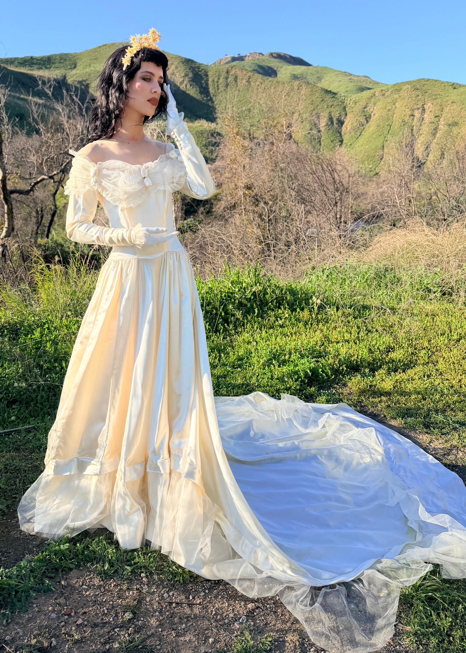 Woman in a white wedding dress standing in a natural setting with mountains in the background