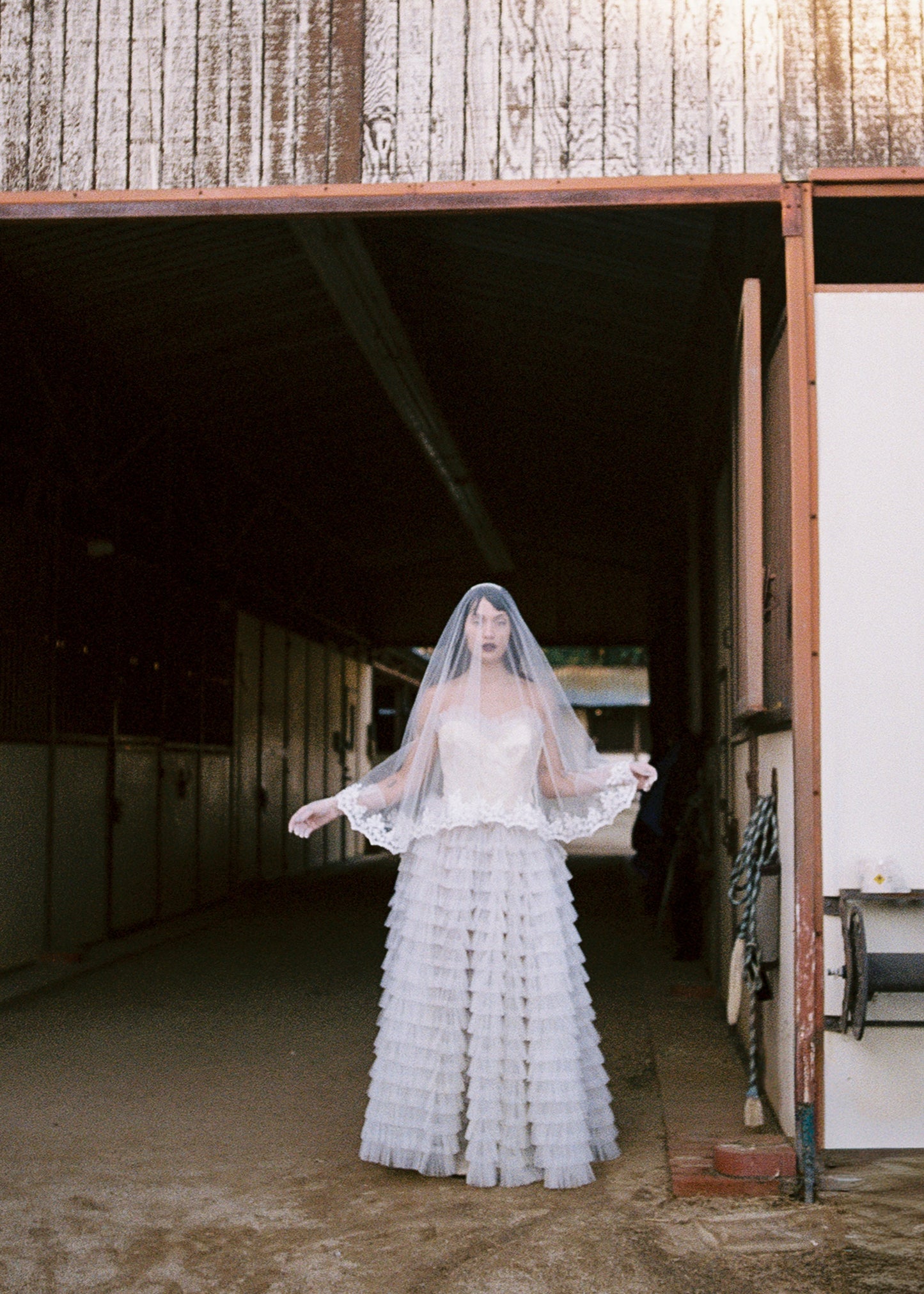 Woman in a white wedding dress standing in front of a rustic building.