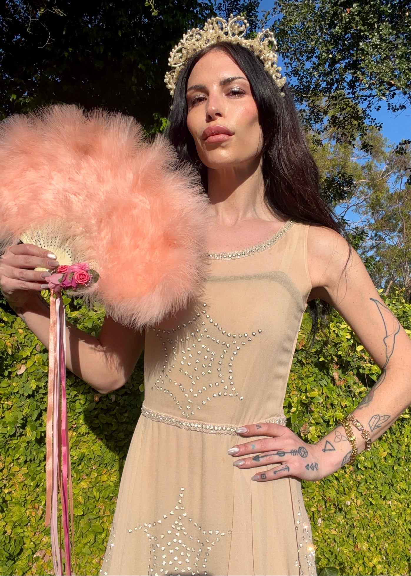 Beige antique 1920's silk chiffon dress with star or spider web design embellishments made from rhinestones worn by a person outdoors.
