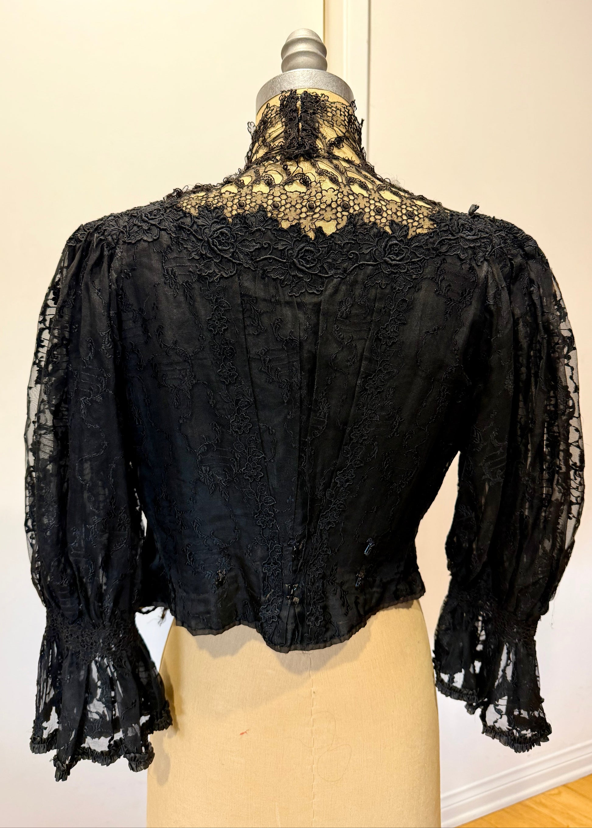 1890's Victorian mourning corset Black lace garment on a mannequin with a plain background