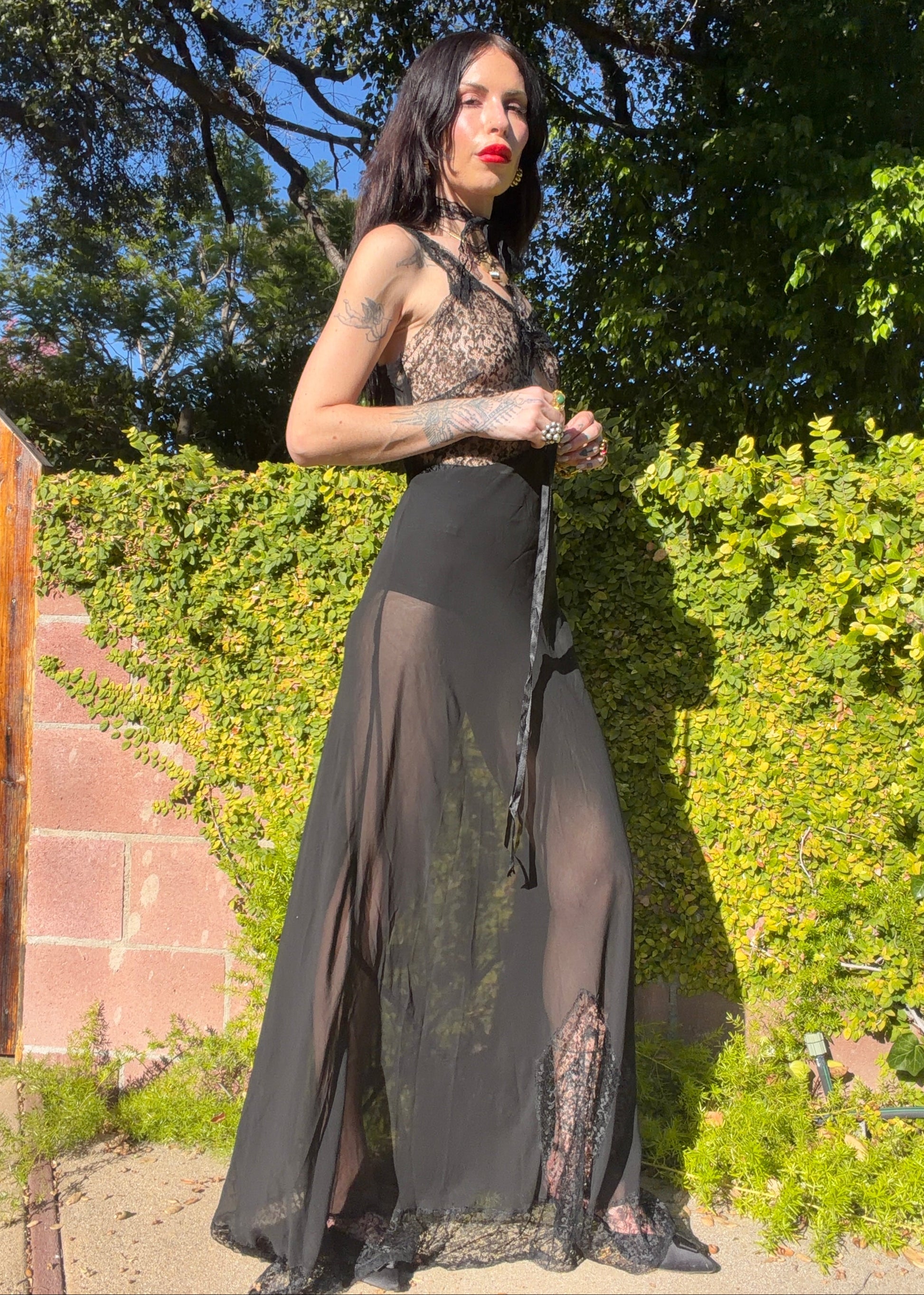 Woman in an antique 1930's floral dress with a headpiece standing outdoors with greenery in the background