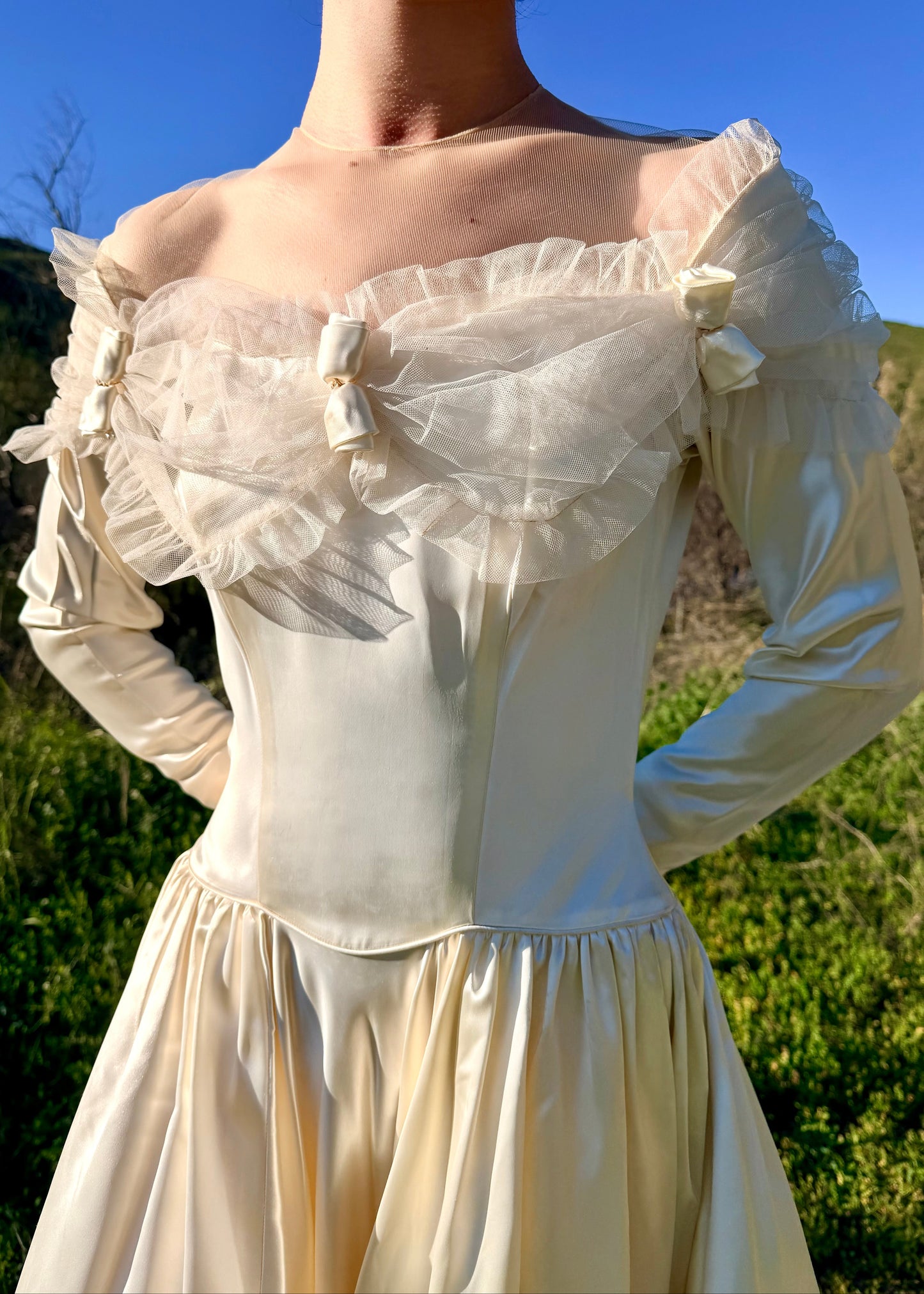 Vintage-style cream-colored dress with ruffled details against a natural background