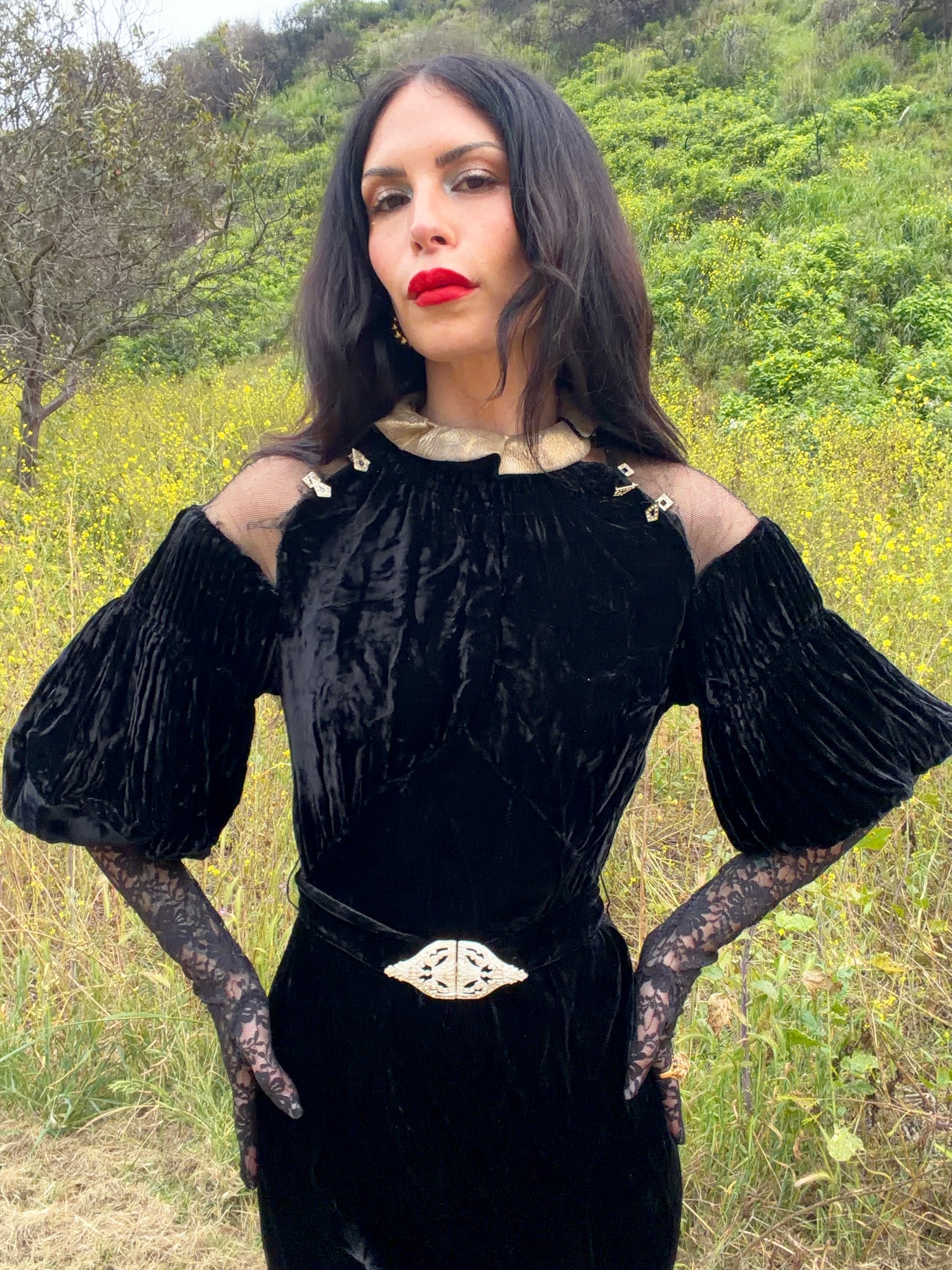 Woman wears antique 1930's black silk velvet Art Deco evening gown in field
