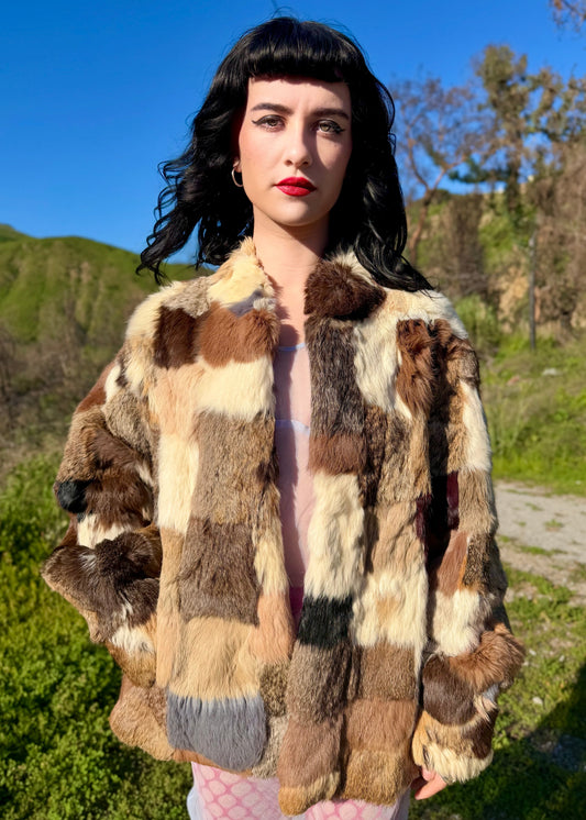 Woman wearing a patchwork fur coat outdoors with mountains in the background