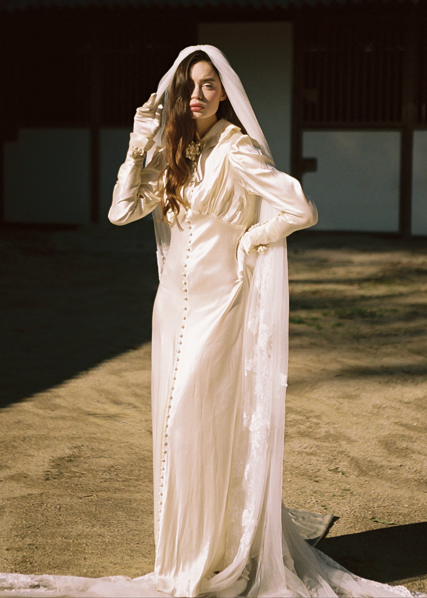 Woman in a long, light-colored dress standing outdoors with a blurred background