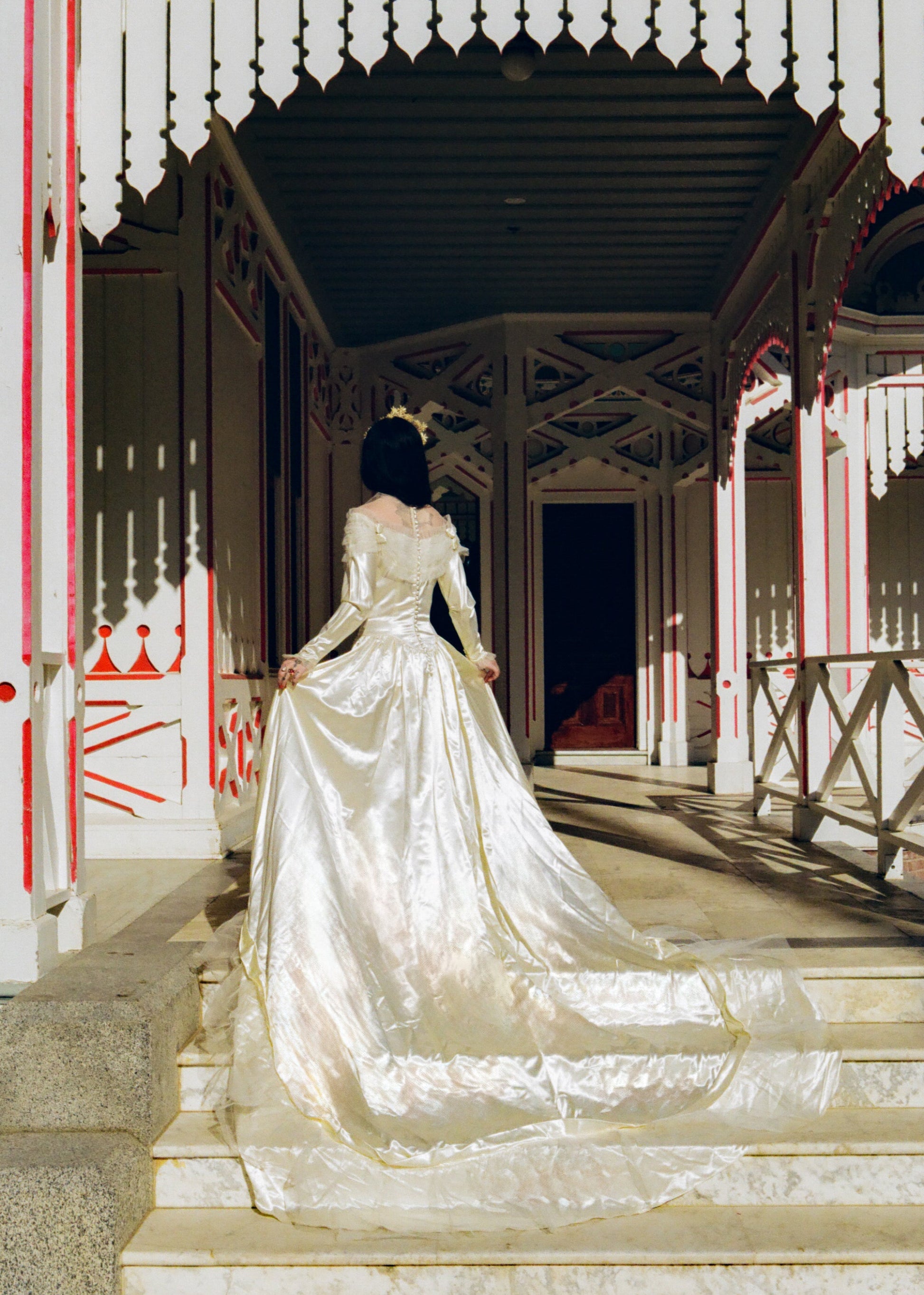 Woman in a white gown standing on a staircase with a decorative railing.