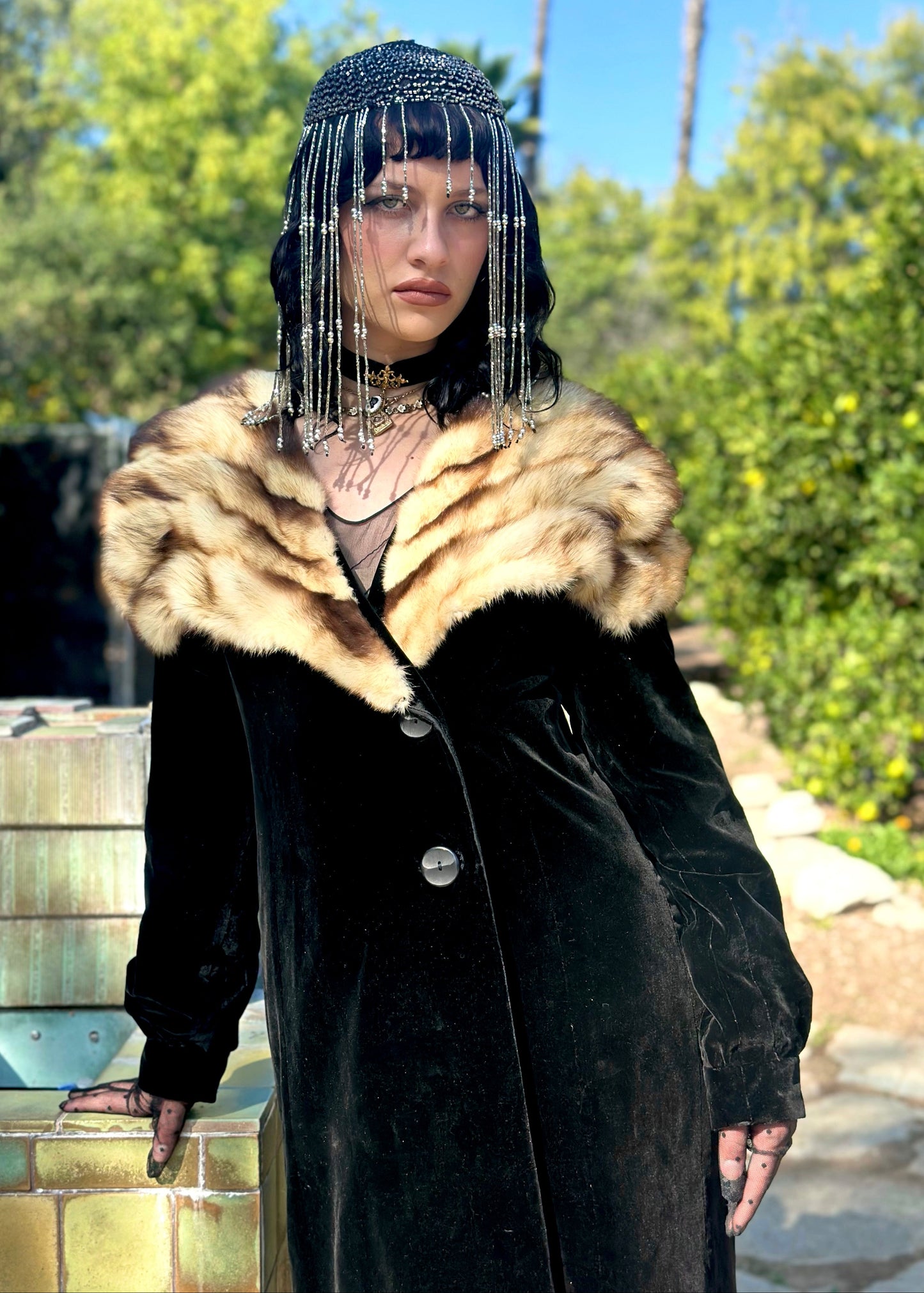 Person wearing an antique black coat with a fur collar outdoors