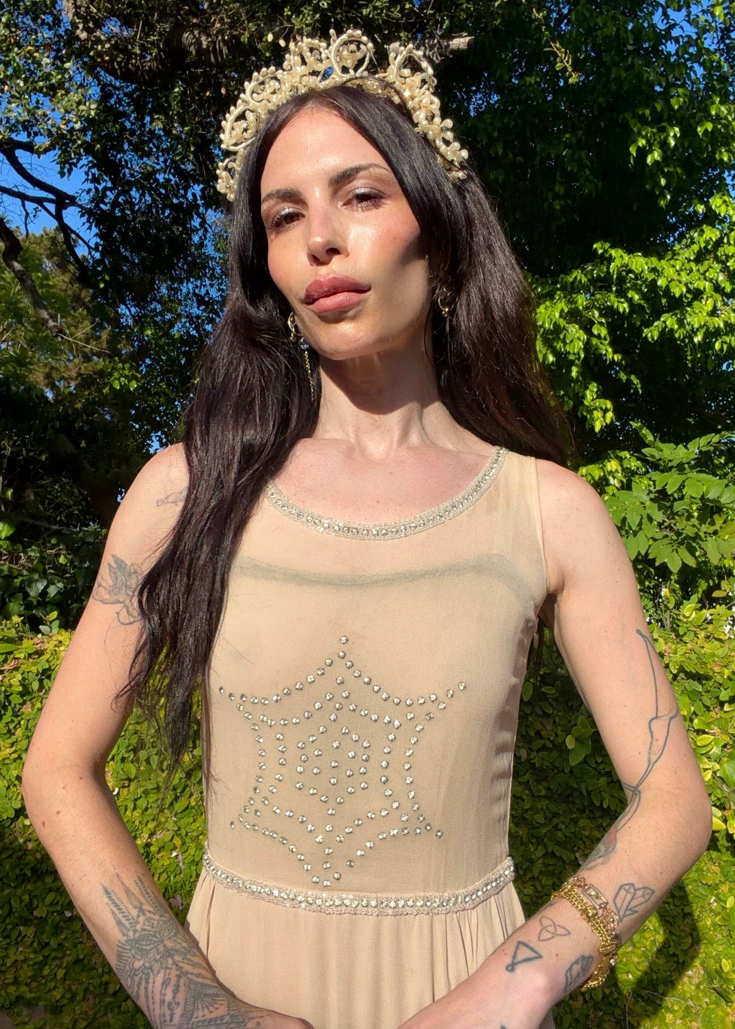 Beige antique 1920's silk chiffon dress with star or spider web design embellishments made from rhinestones worn by a person outdoors.