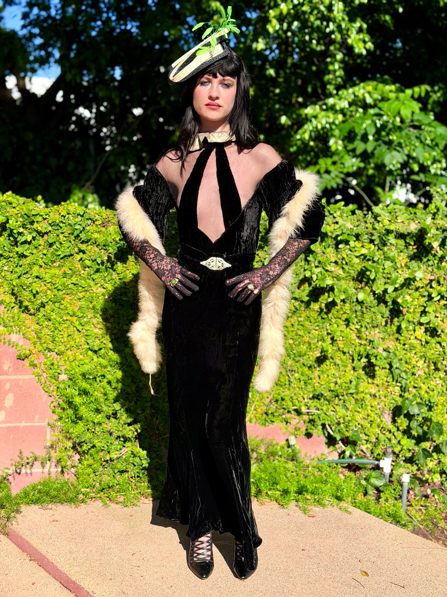 Woman wears antique 1930's black silk velvet Art Deco evening gown in field