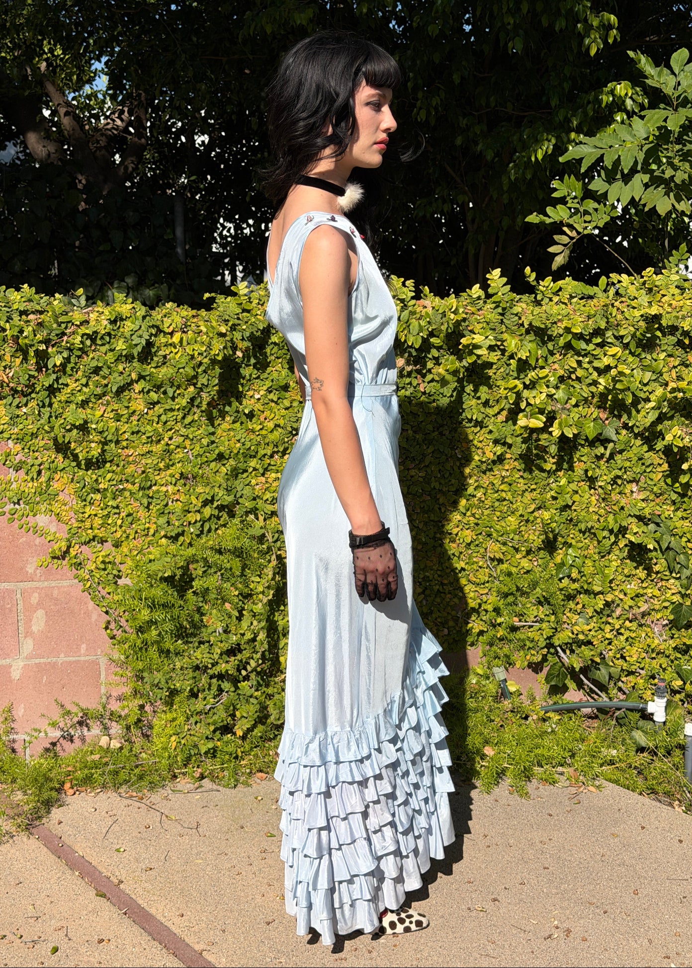 Woman wears antique 1930's silk taffeta gown in ice blue with tiered ruffle mermaid skirt hemline and removeable art deco belt