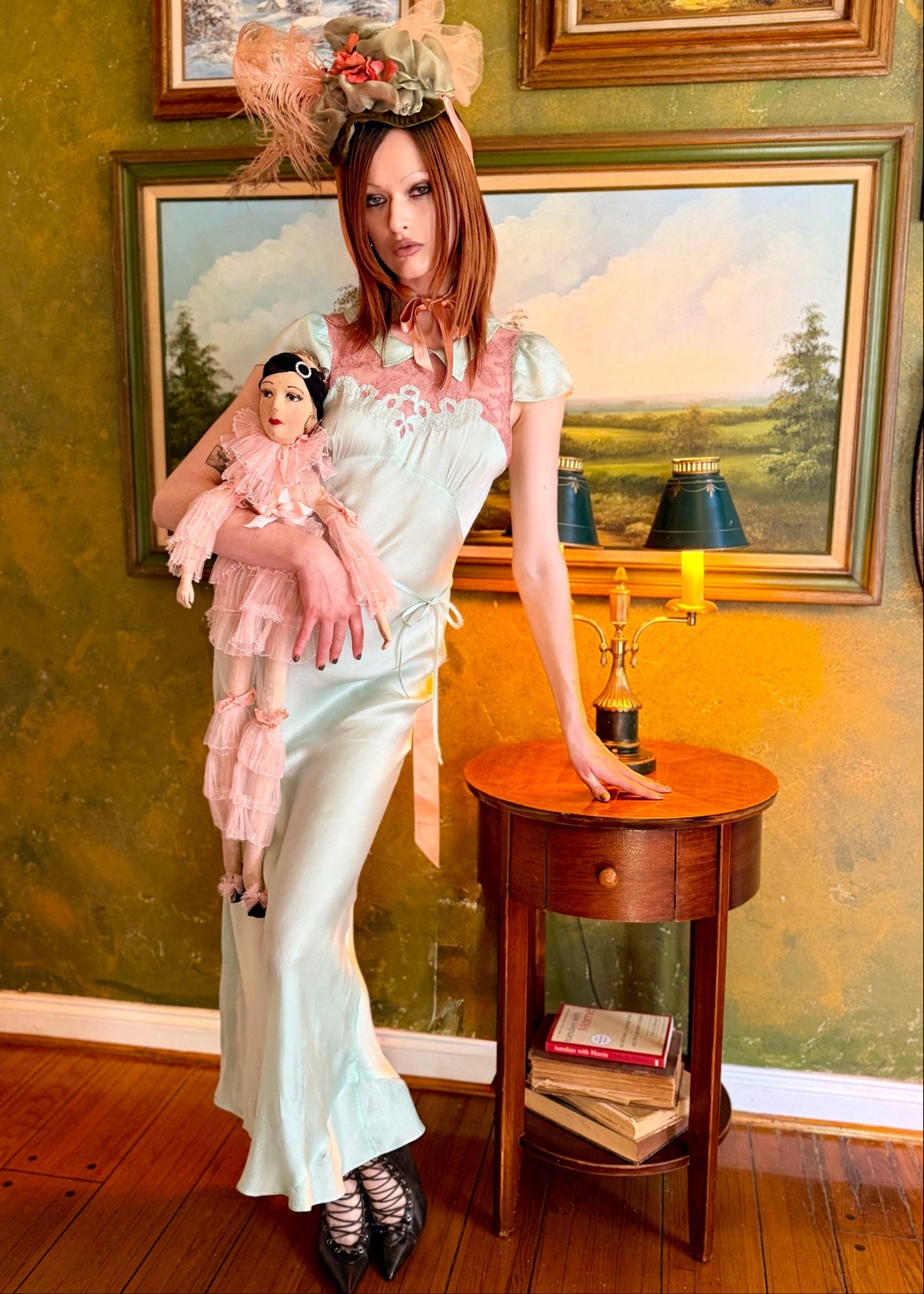 Woman in an 1930's slip vintage dress  in mint standing in a room with green walls and framed paintings.