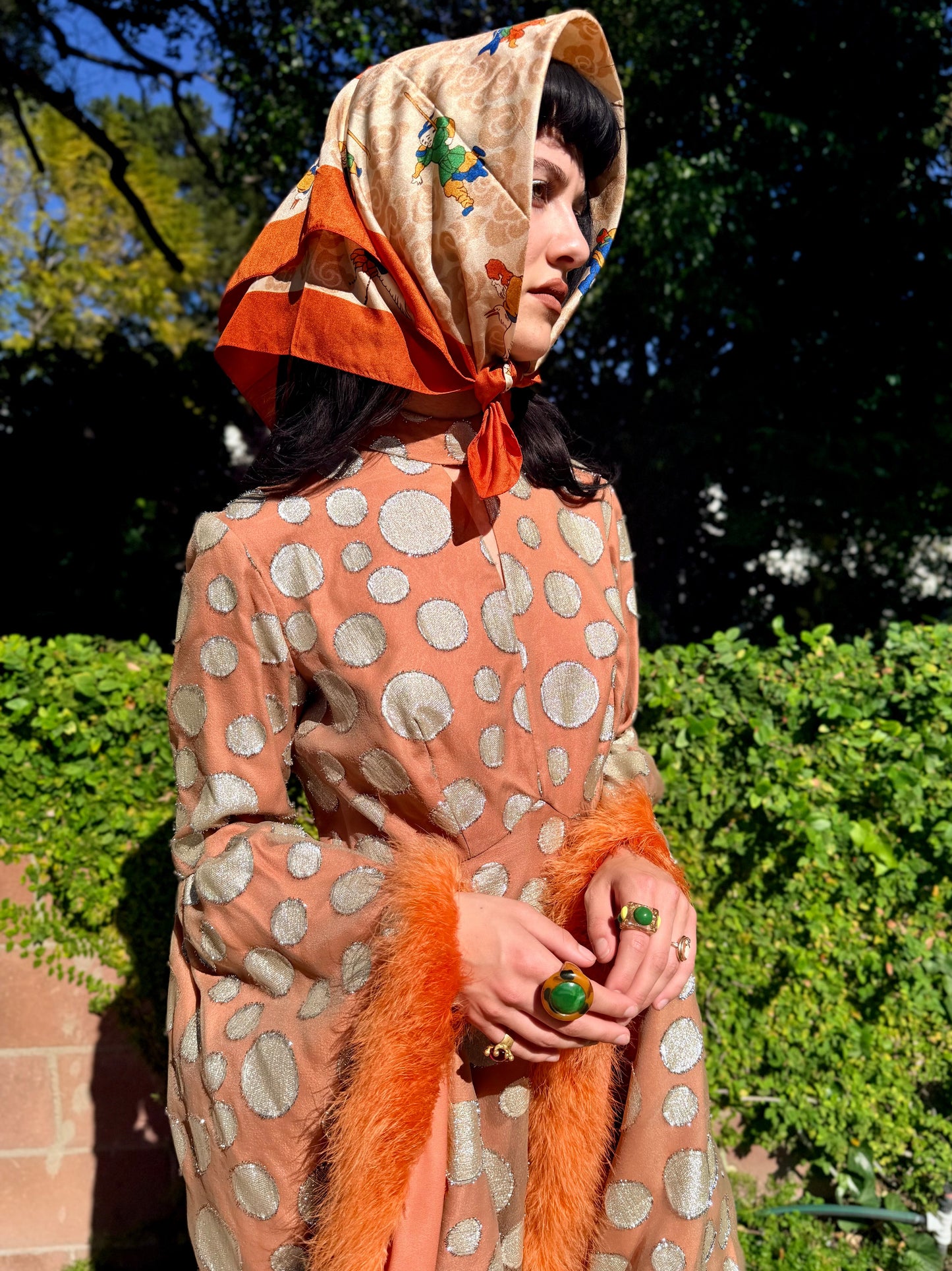 Woman in a vintage 1970's chiffon polka dot maxi dress with marabou feather accents standing outdoors.