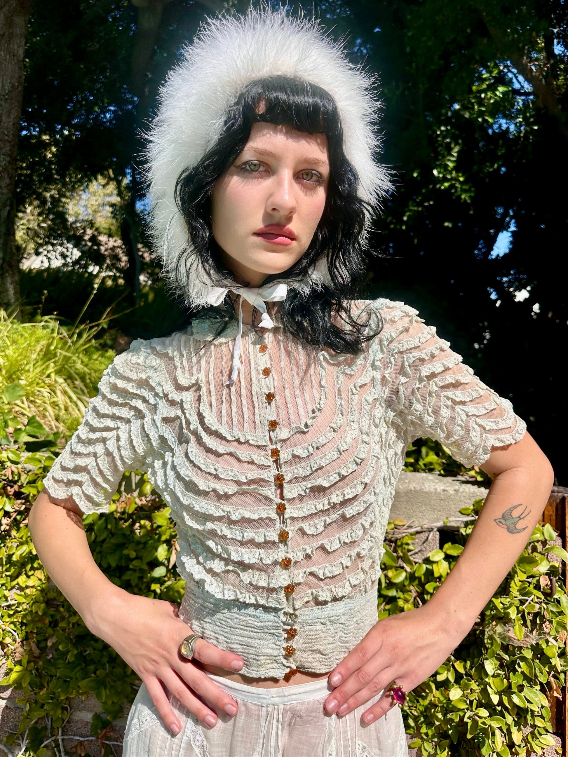 Person wearing a textured white outfit with a fur-lined hood outdoors.