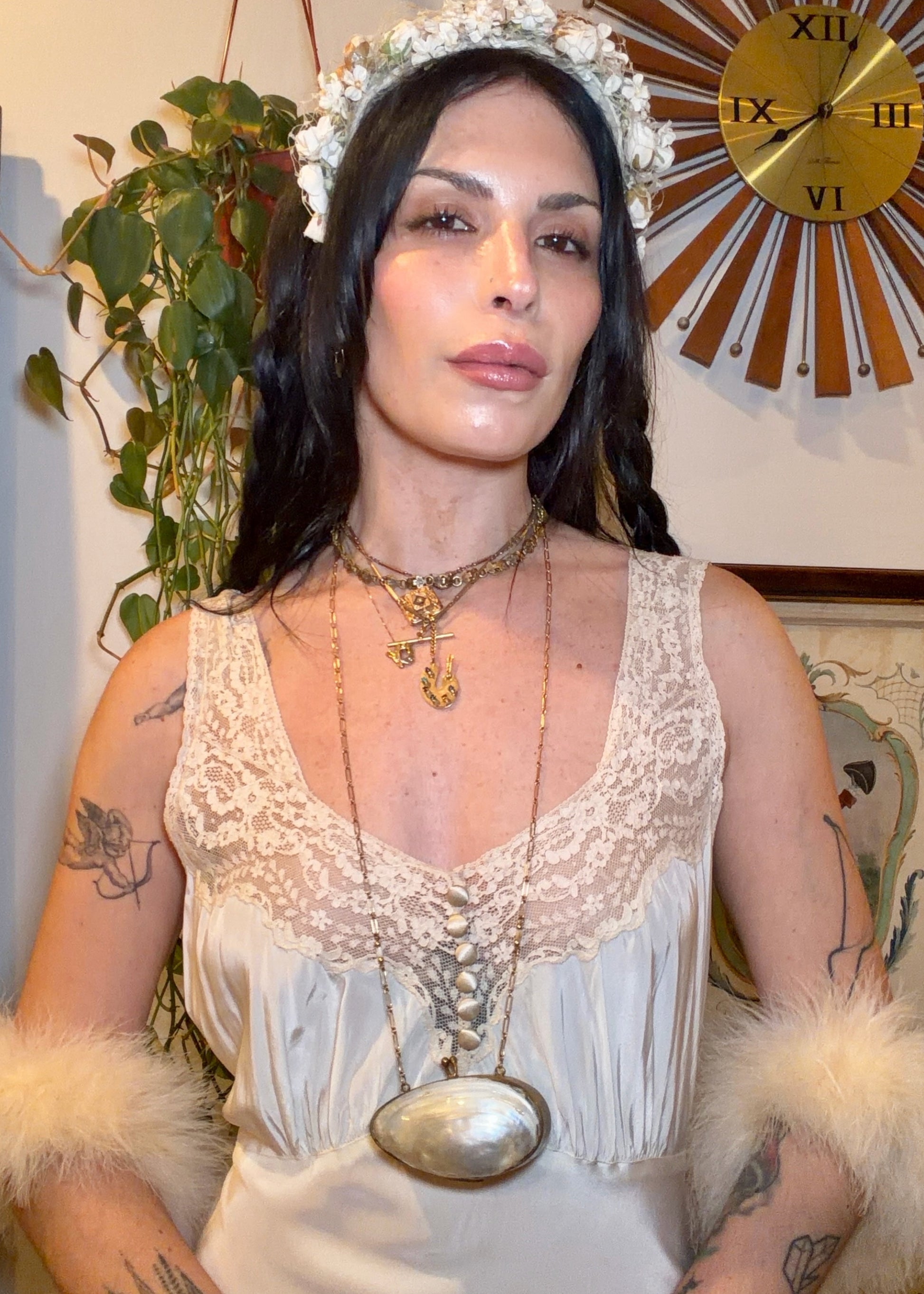 Woman in a white 1930s bias cut dress standing in a room with decorative elements.