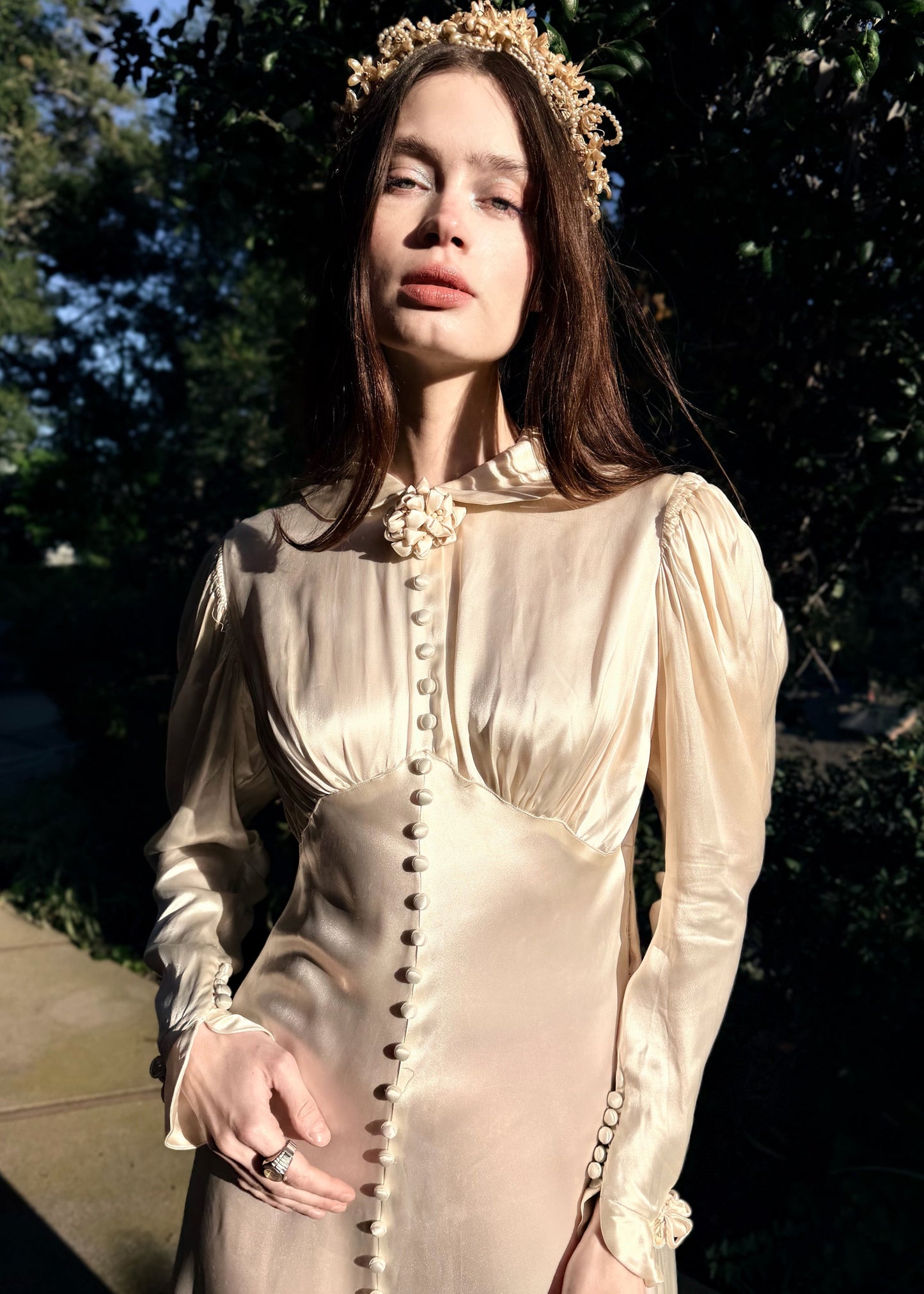 Vintage 1930s wedding gown with long sleeves and decorative buttons on a dark background