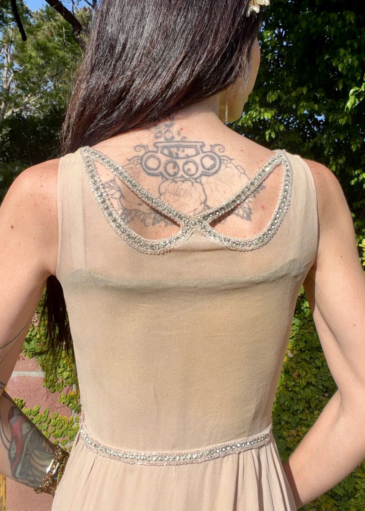 Beige antique 1920's silk chiffon dress with star or spider web design embellishments made from rhinestones worn by a person outdoors.