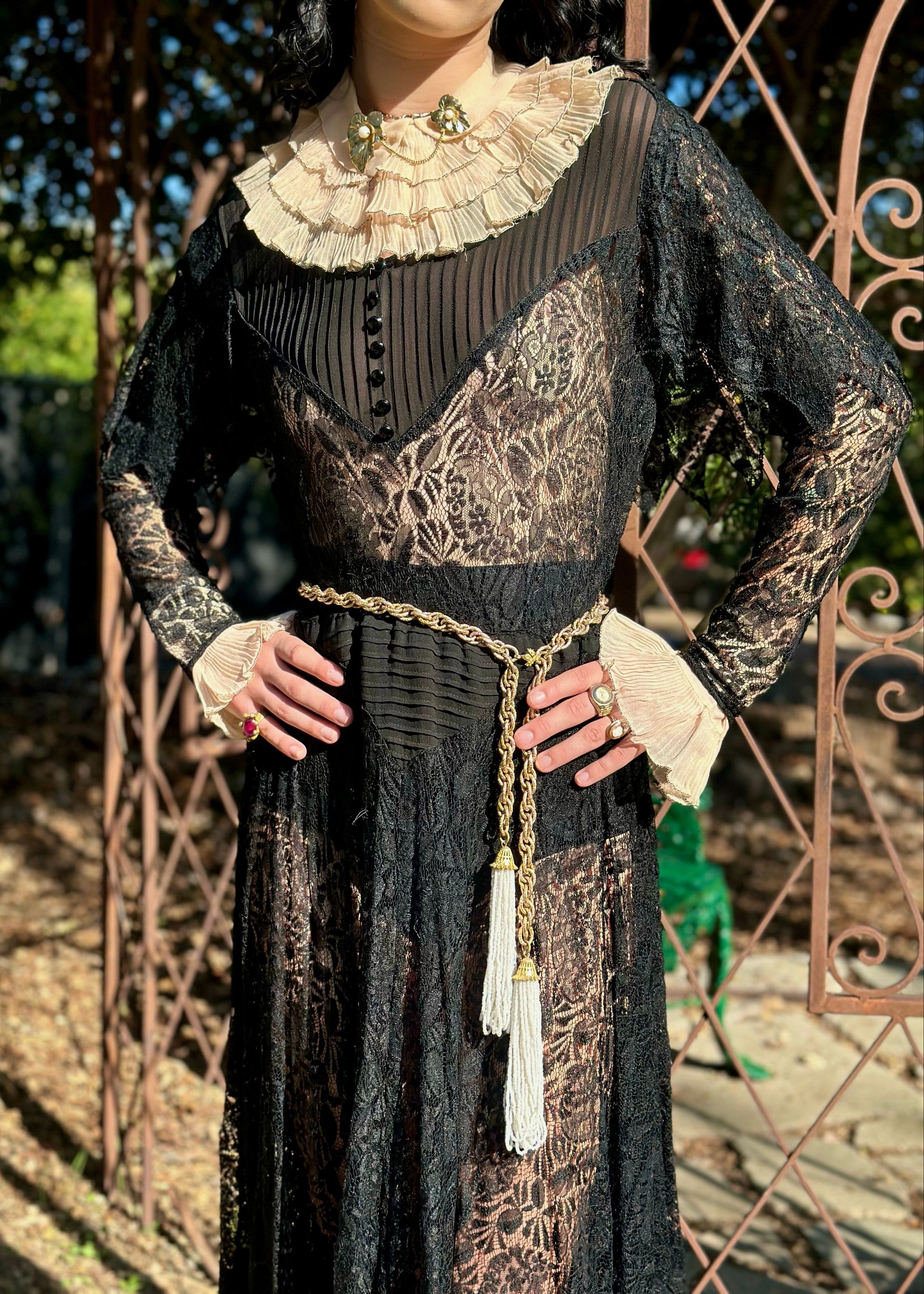 Person wearing a black lace dress with intricate details outdoors.