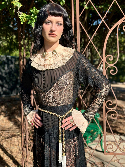Woman in a vintage-style dress standing in front of an ornate metal gate.