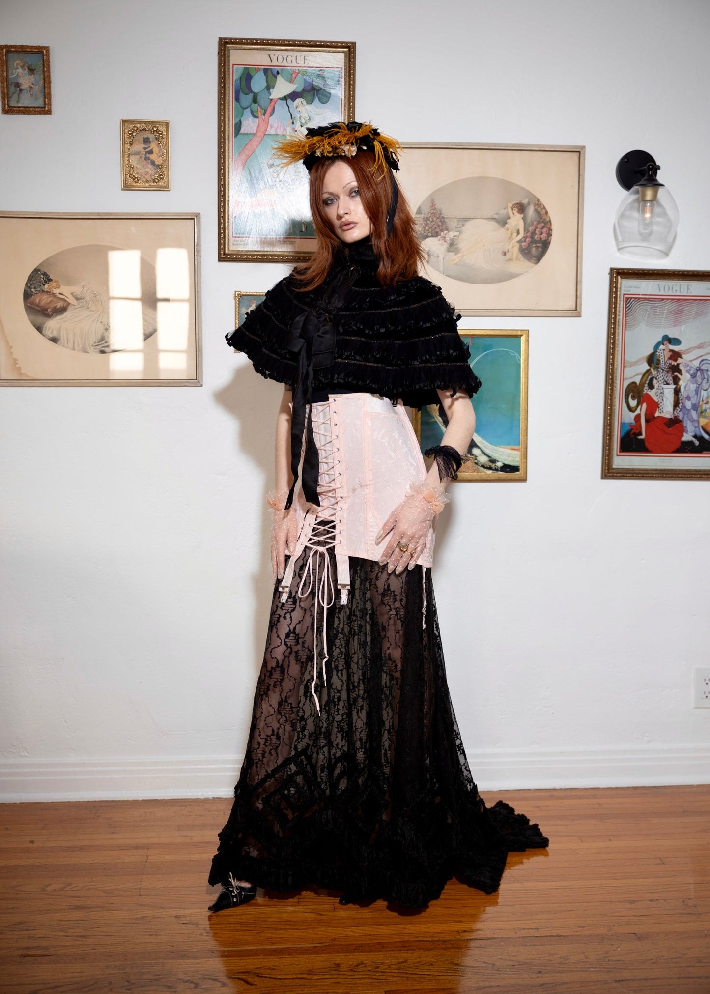Woman in a black and pink dress standing in an art gallery with framed pictures on the wall.