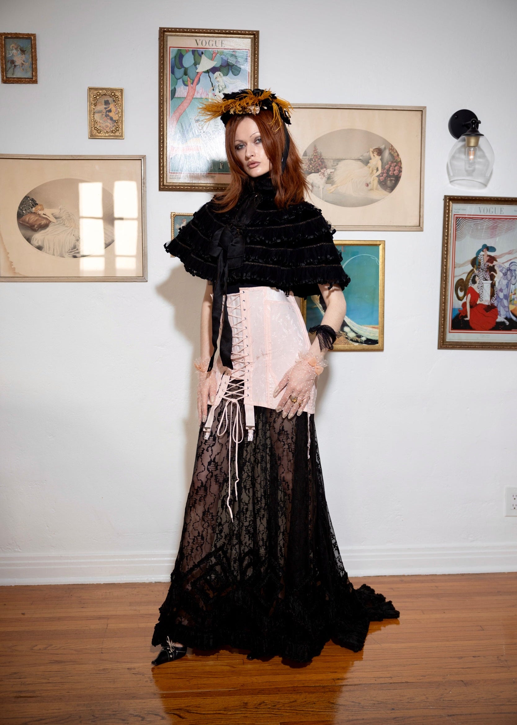 Woman in a black and pink dress standing in an art gallery with framed pictures on the wall.