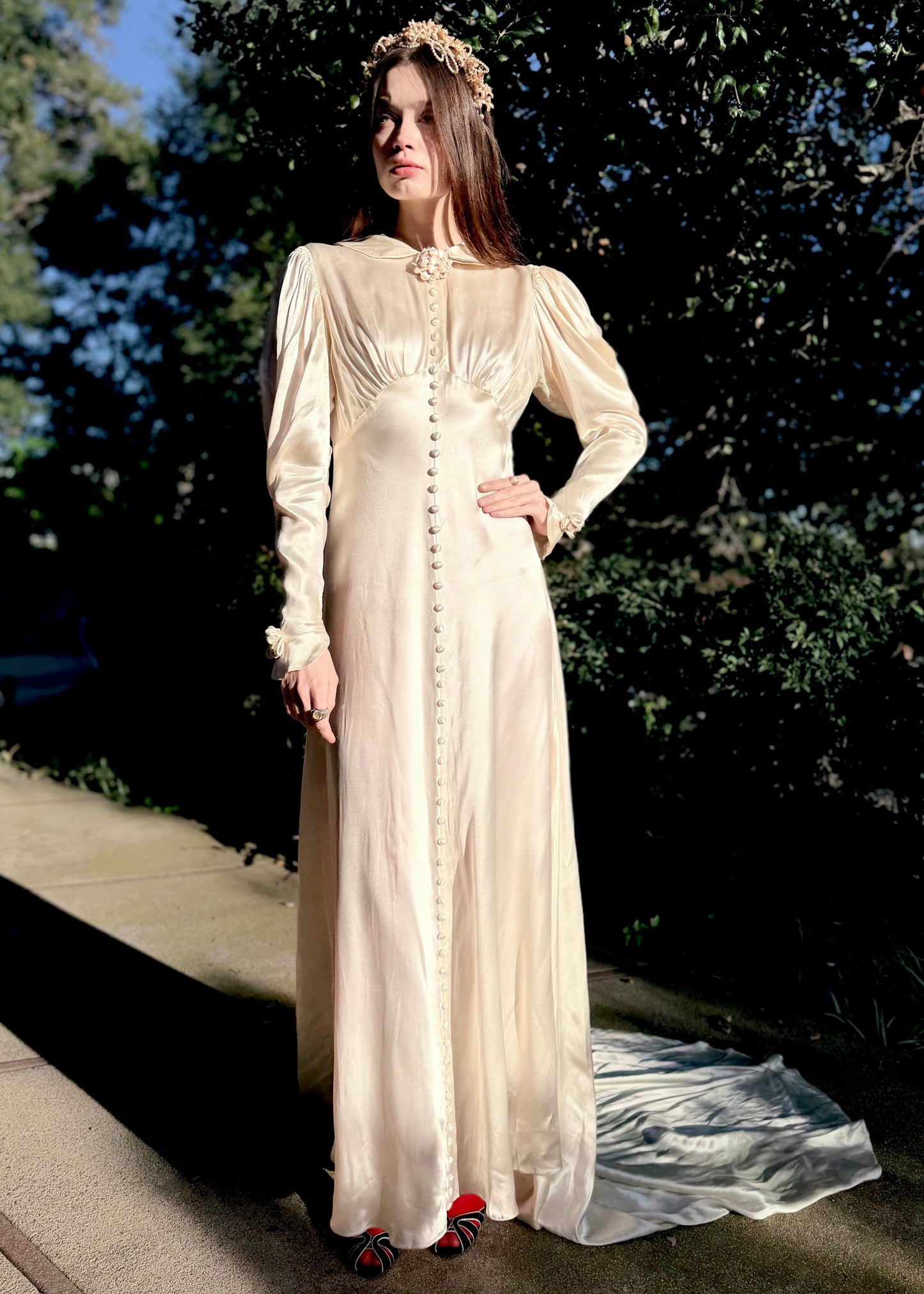 Vintage 1930s wedding gown with long sleeves and decorative buttons on a dark background