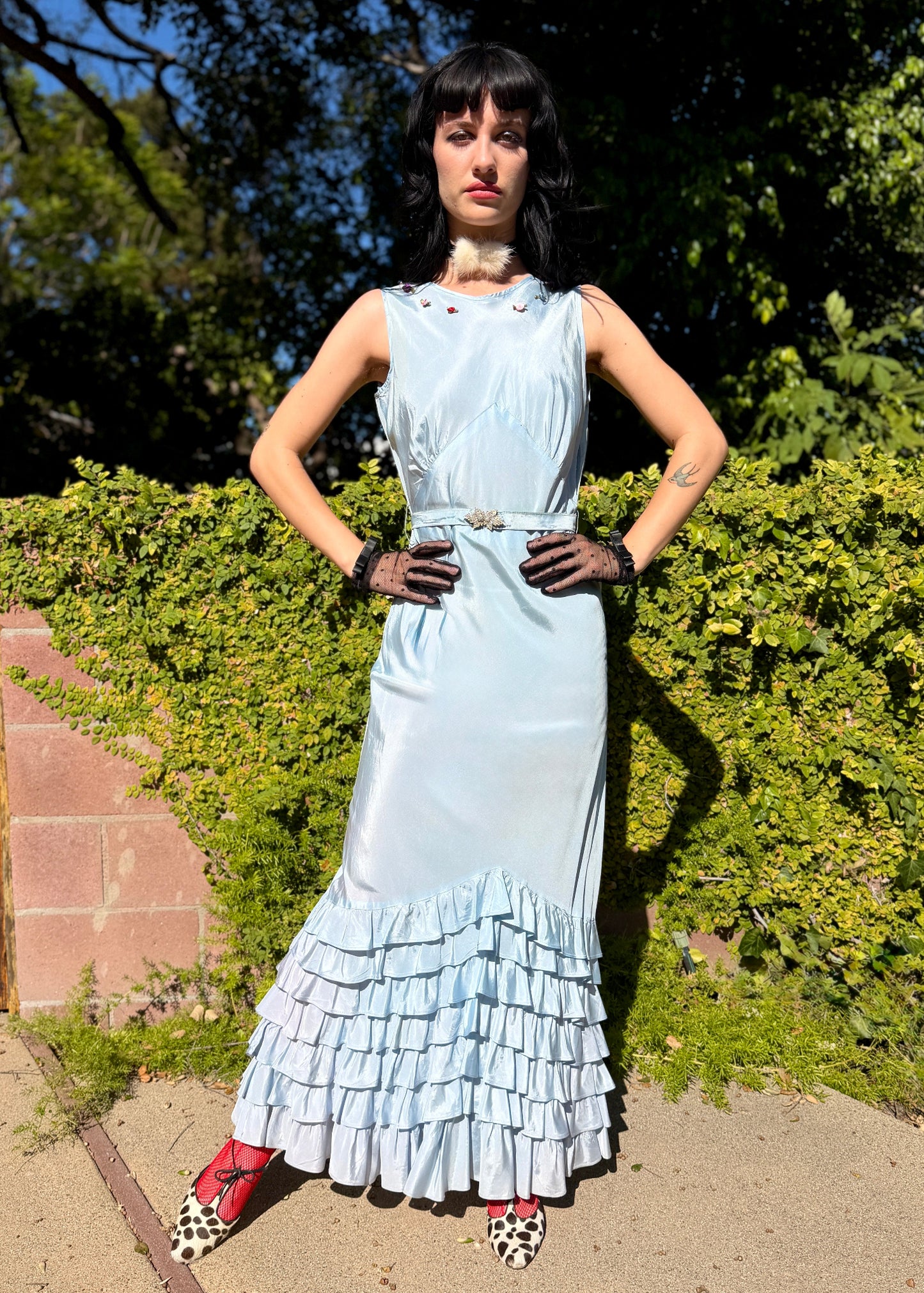 Woman wears antique 1930's silk taffeta gown in ice blue with tiered ruffle mermaid skirt hemline and removeable art deco belt