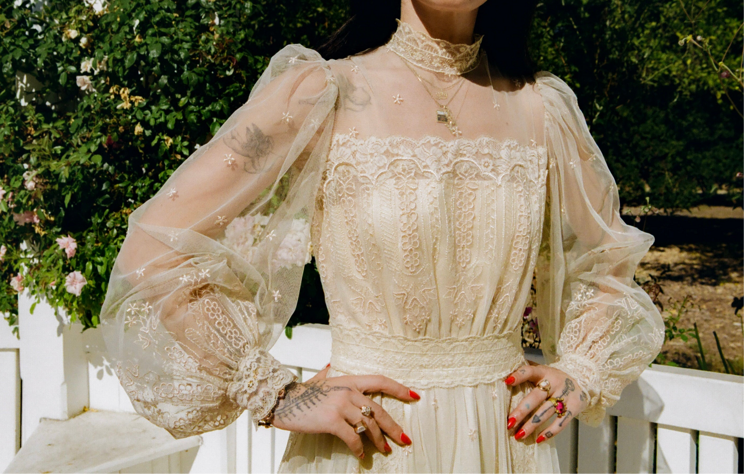 Person wearing a vintage-style lace dress with sheer sleeves in an outdoor setting.