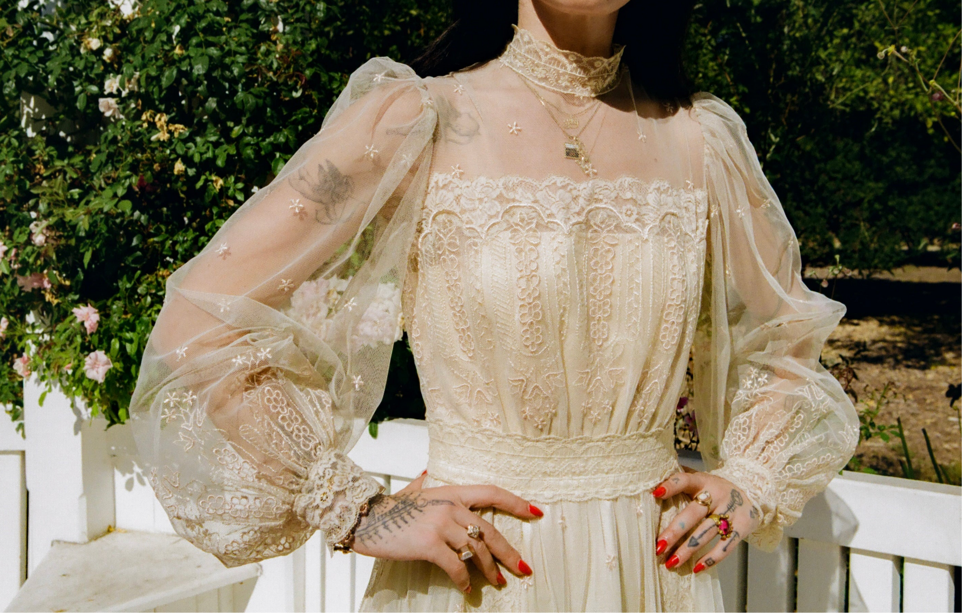 Person wearing a vintage-style lace dress with sheer sleeves in an outdoor setting.