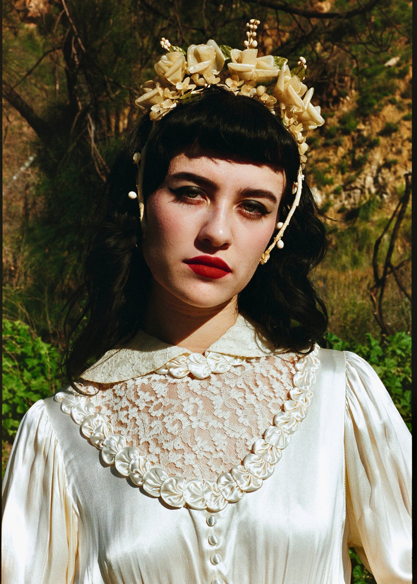 Woman wearing a white lace dress and headpiece with flowers outdoors