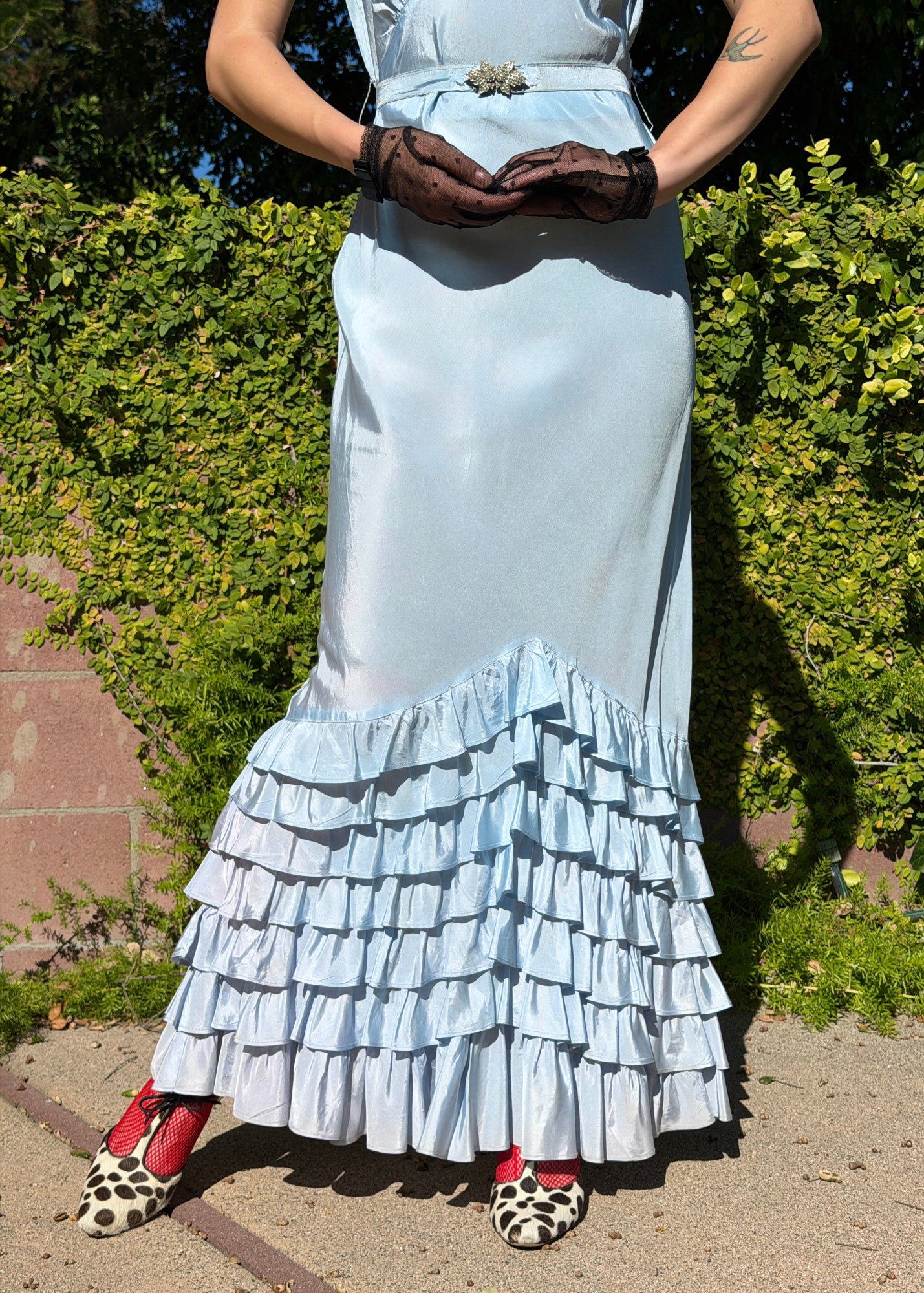 Woman wears antique 1930's silk taffeta gown in ice blue with tiered ruffle mermaid skirt hemline and removeable art deco belt