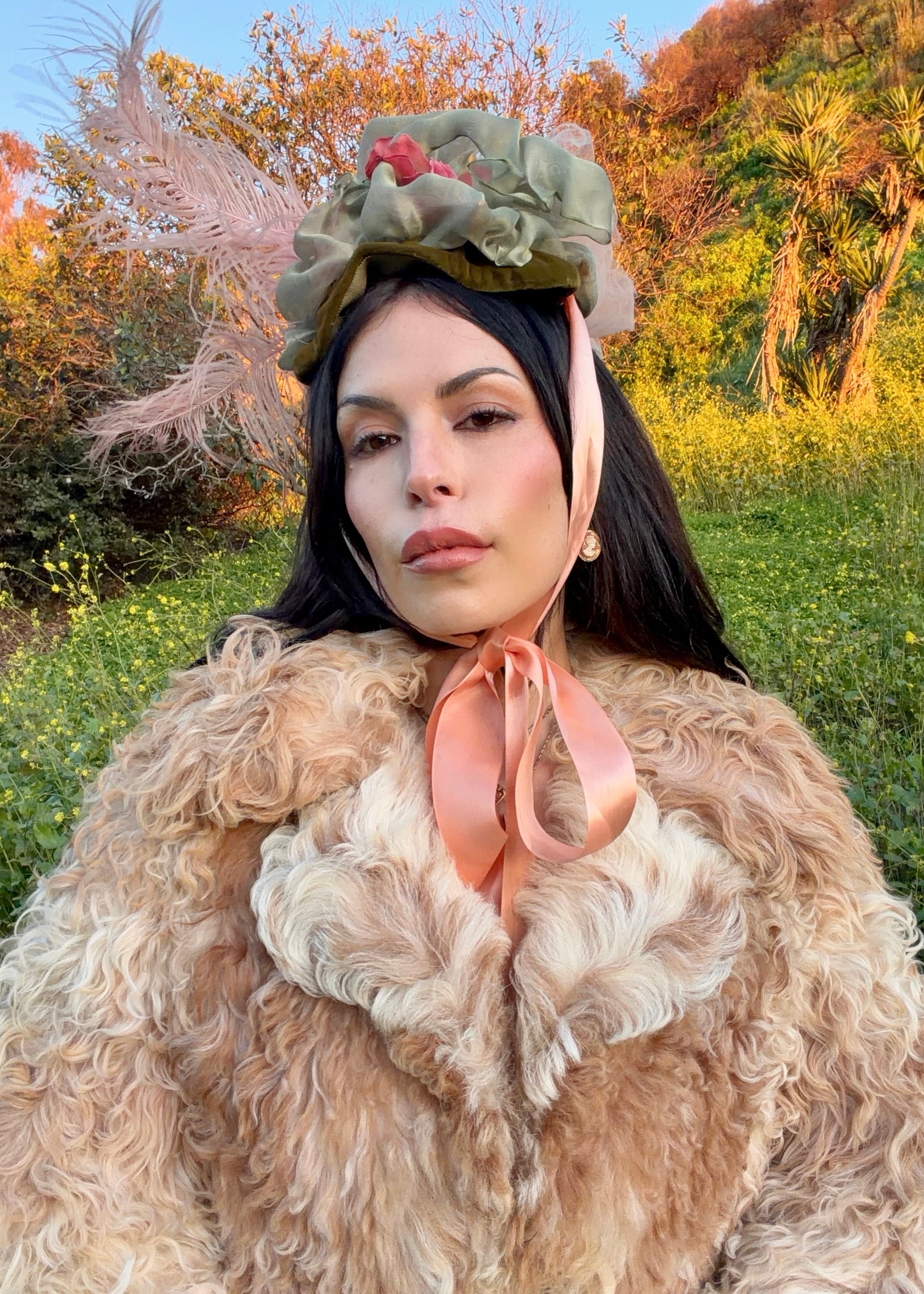 Woman wearing a floral headpiece and beige fur coat in a natural setting