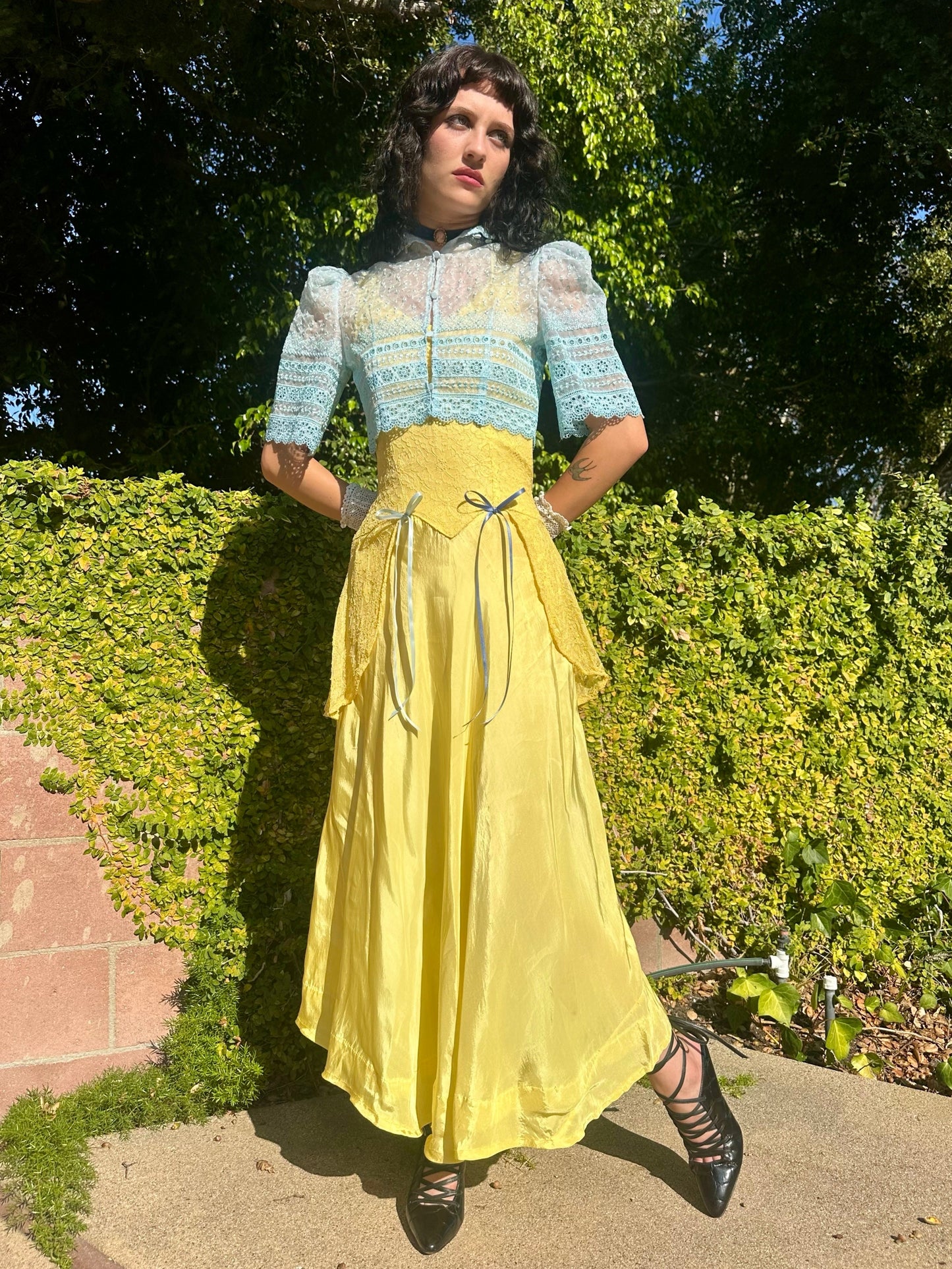 Woman in a vintage-style outfit with a blue top and yellow skirt standing outdoors.