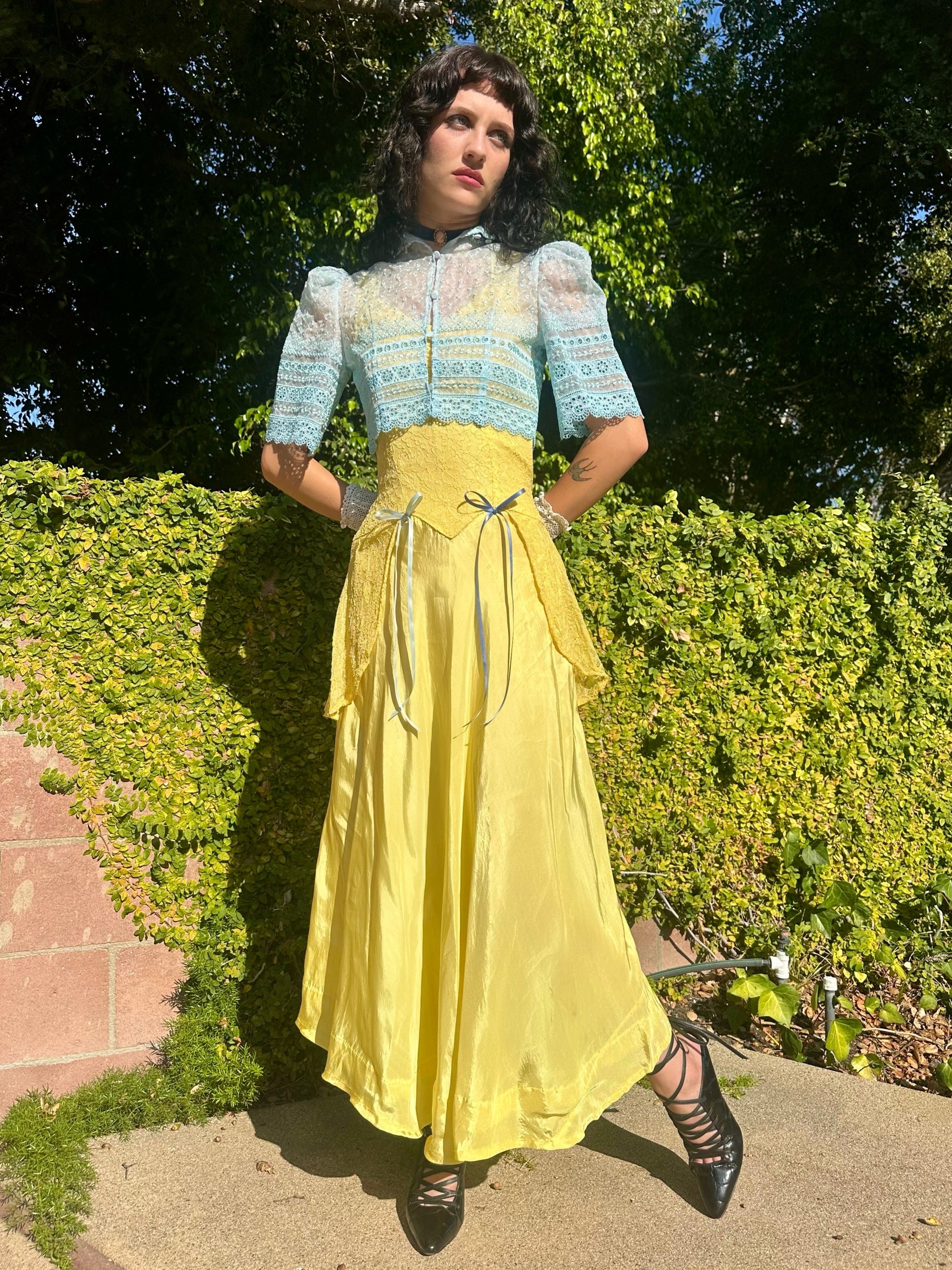 Woman in a vintage-style outfit with a blue top and yellow skirt standing outdoors.