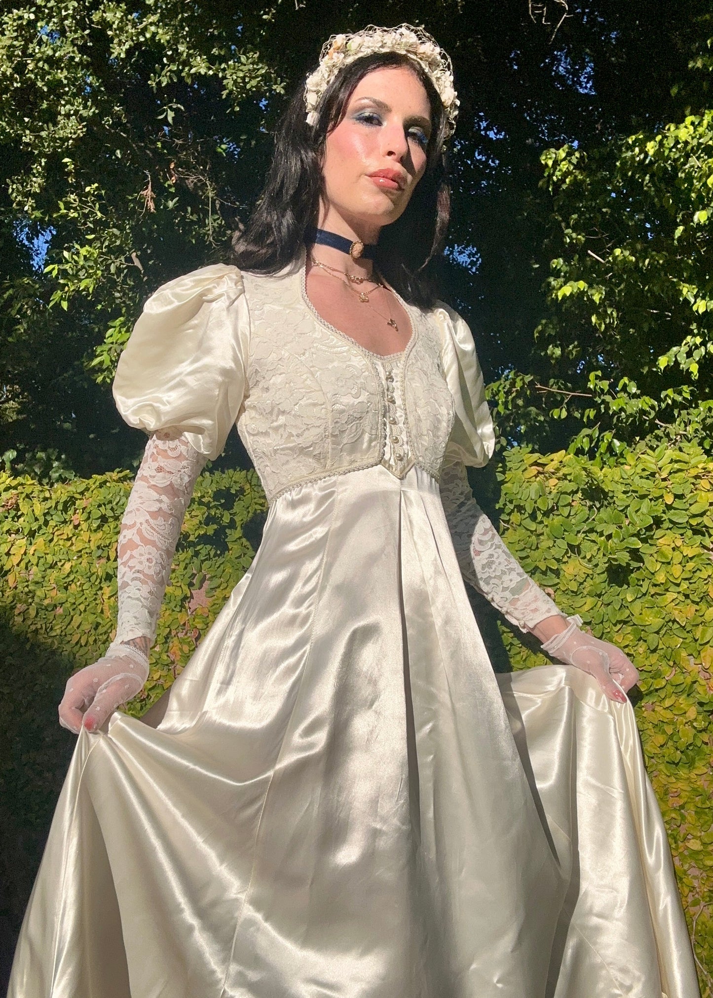 Person in a vintage Gunne Sax wedding dress with puffed sleeves and lace gloves standing outdoors.