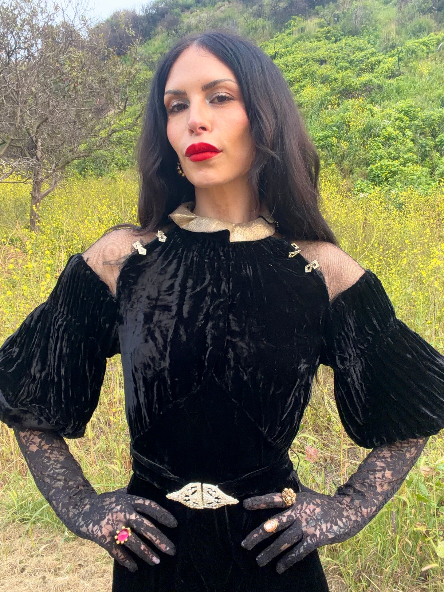 Woman wears antique 1930's black silk velvet Art Deco evening gown in field
