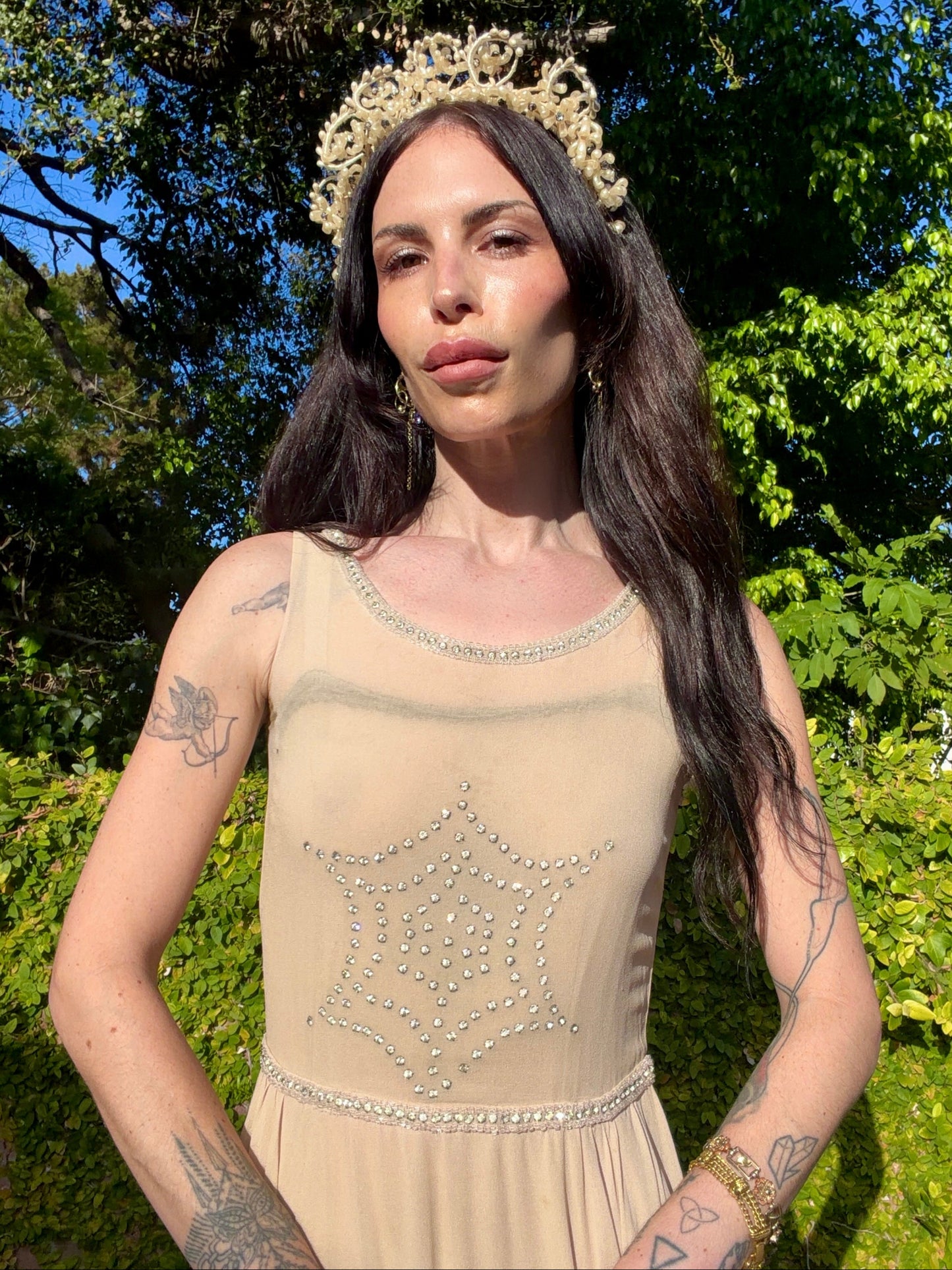 Beige antique 1920's silk chiffon dress with star or spider web design embellishments made from rhinestones worn by a person outdoors.