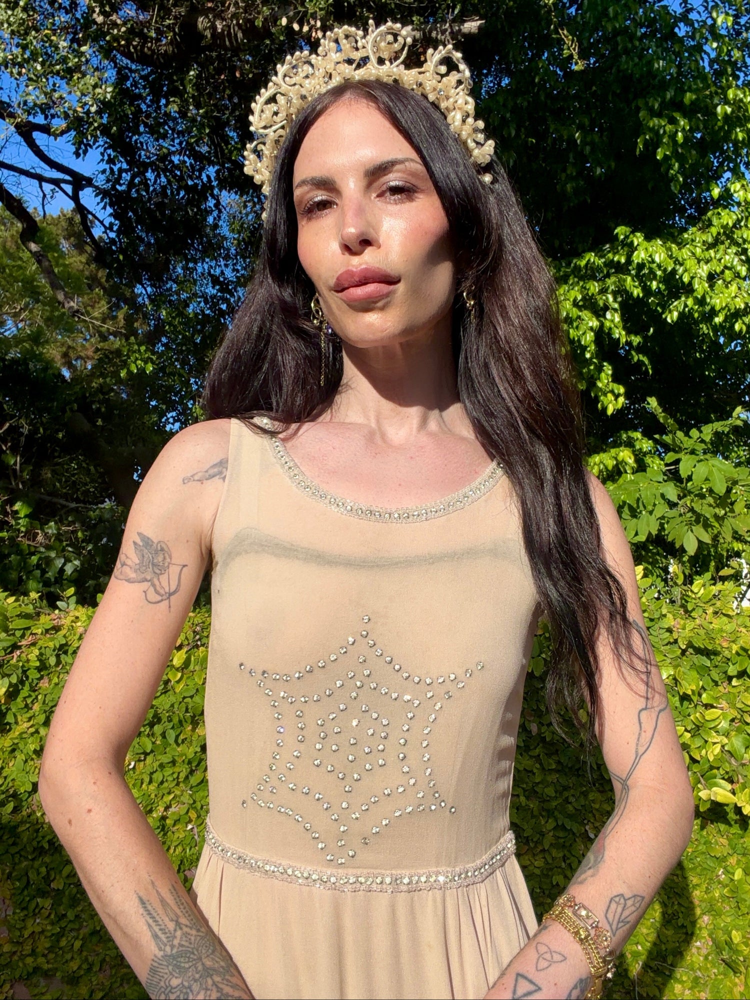 Beige antique 1920's silk chiffon dress with star or spider web design embellishments made from rhinestones worn by a person outdoors.