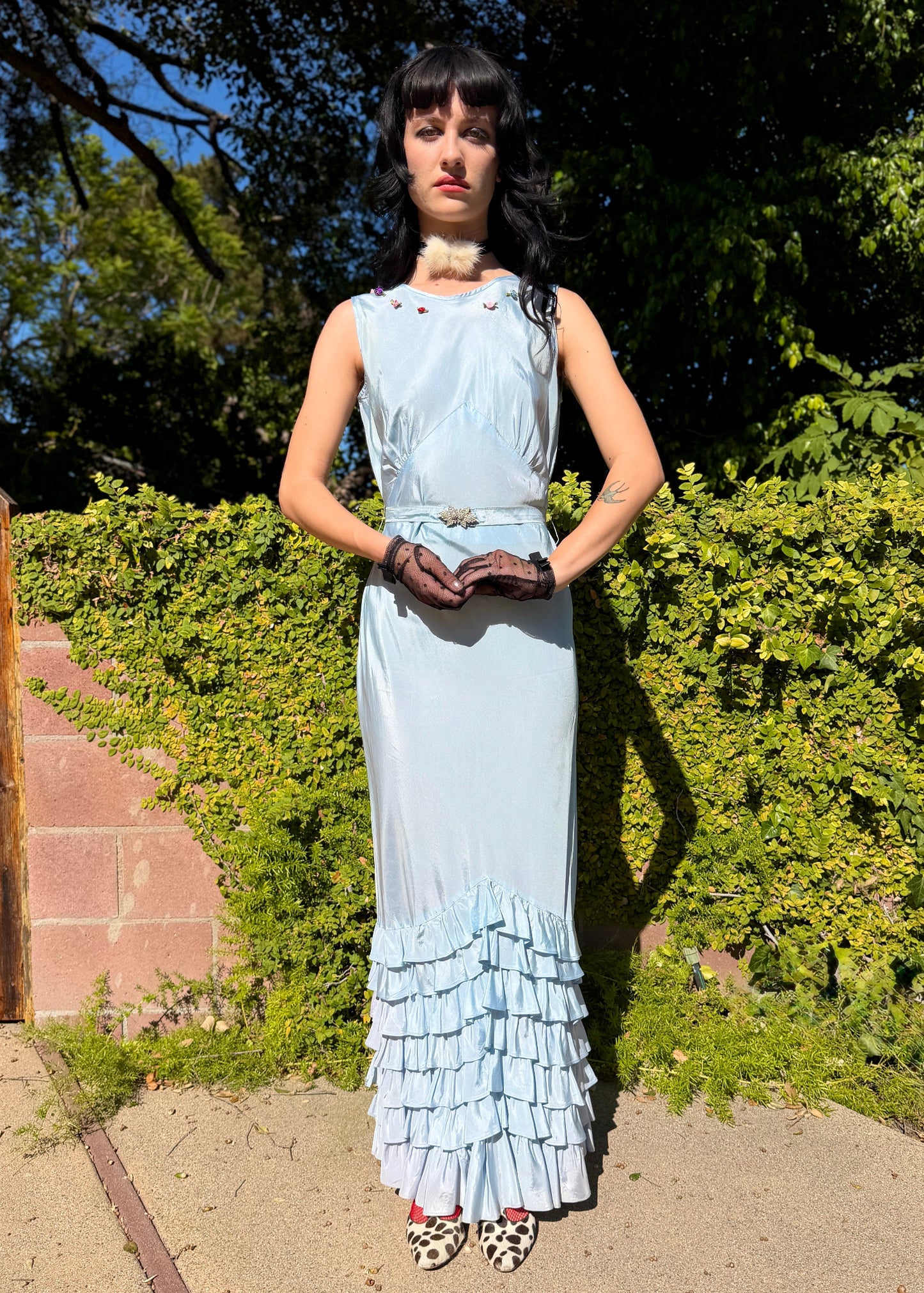 Woman wears antique 1930's silk taffeta gown in ice blue with tiered ruffle mermaid skirt hemline and removeable art deco belt