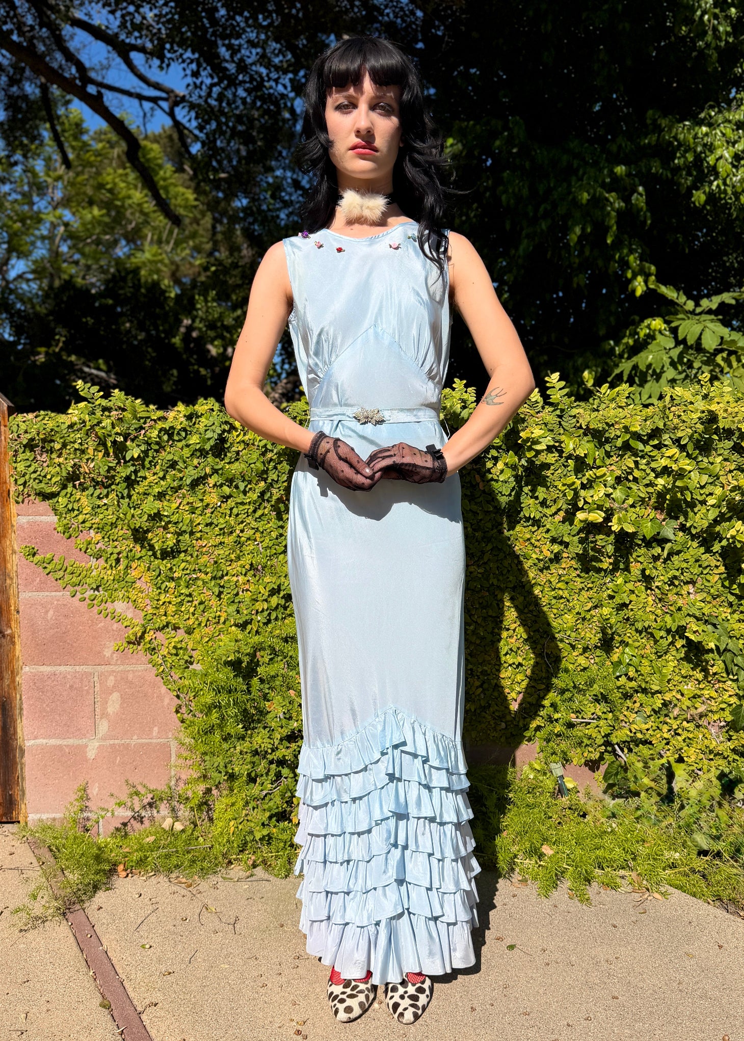 Woman wears antique 1930's silk taffeta gown in ice blue with tiered ruffle mermaid skirt hemline and removeable art deco belt