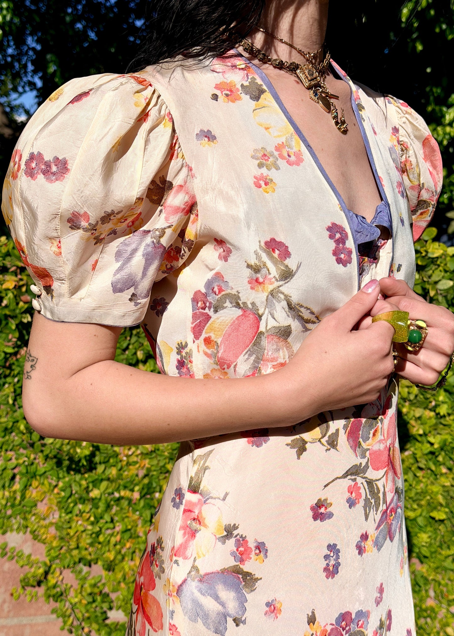 Woman in a floral  antique 1930s floral dress standing outdoors with greenery in the background