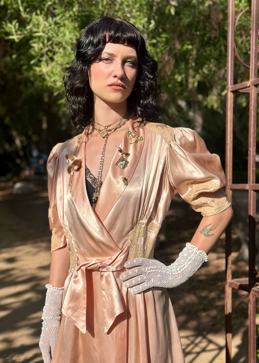 Woman in a vintage-style dress with gloves standing outdoors.
