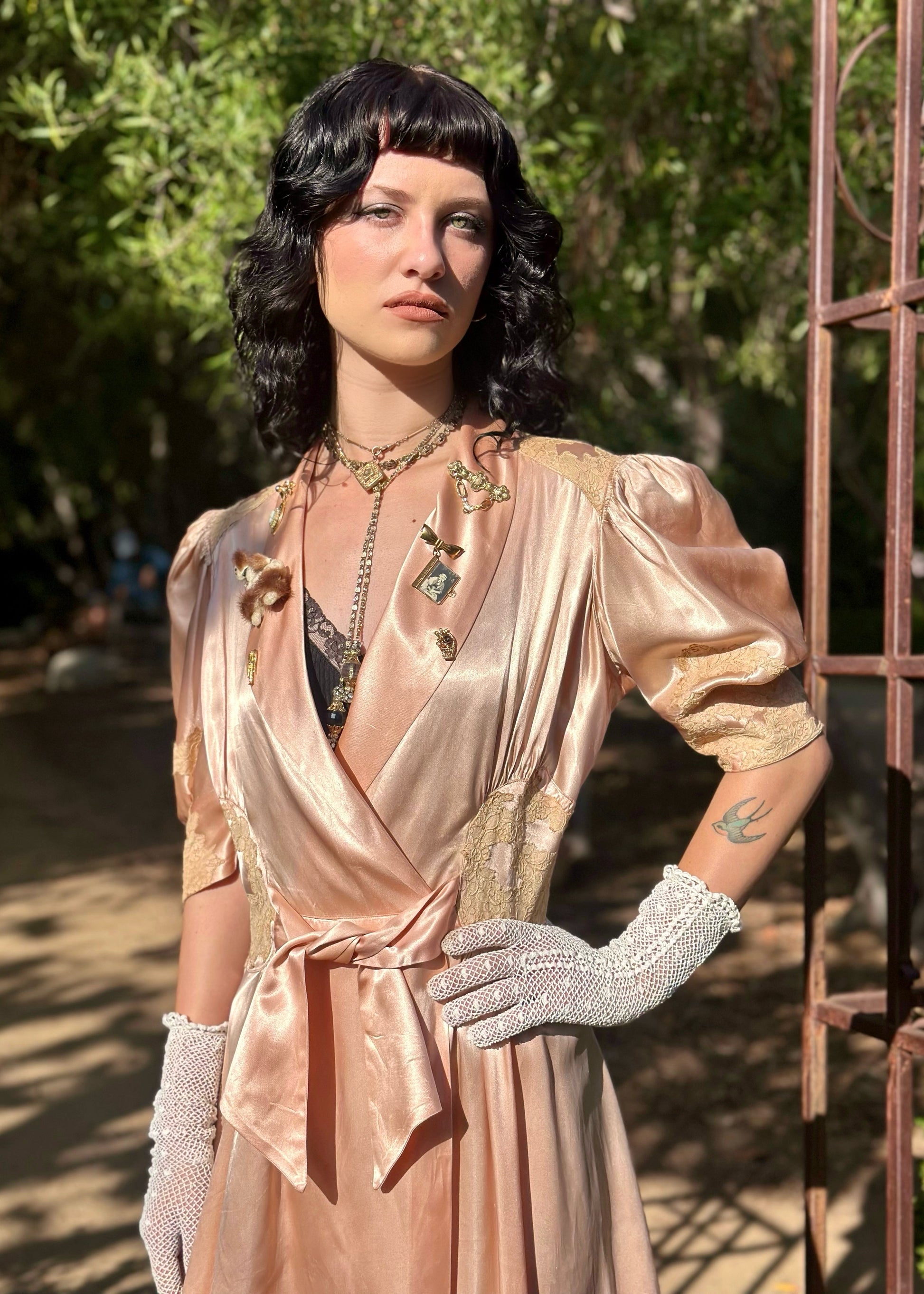 Woman in a vintage-style dress with gloves standing outdoors.