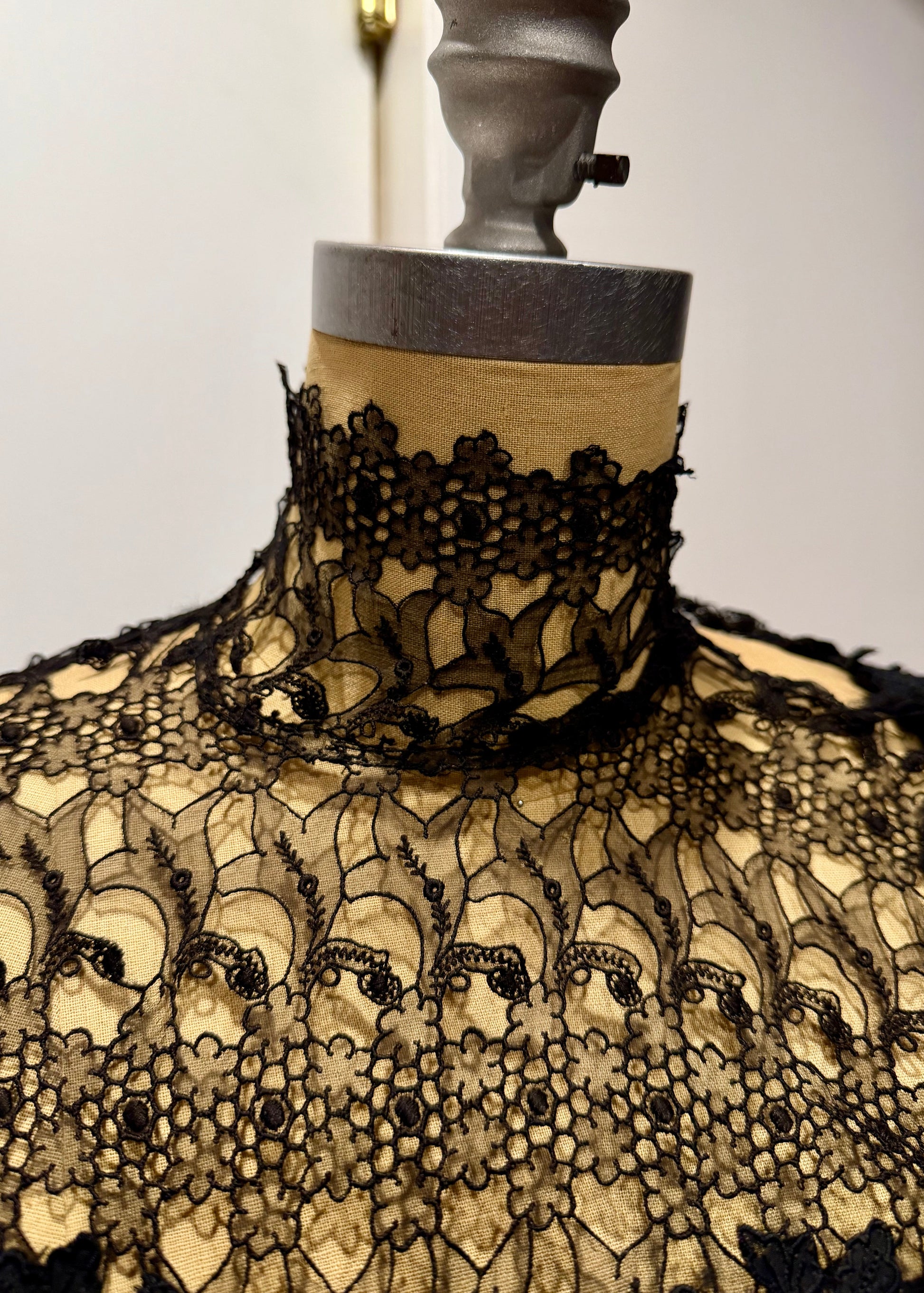 1890's Victorian mourning corset Black lace garment on a mannequin with a plain background