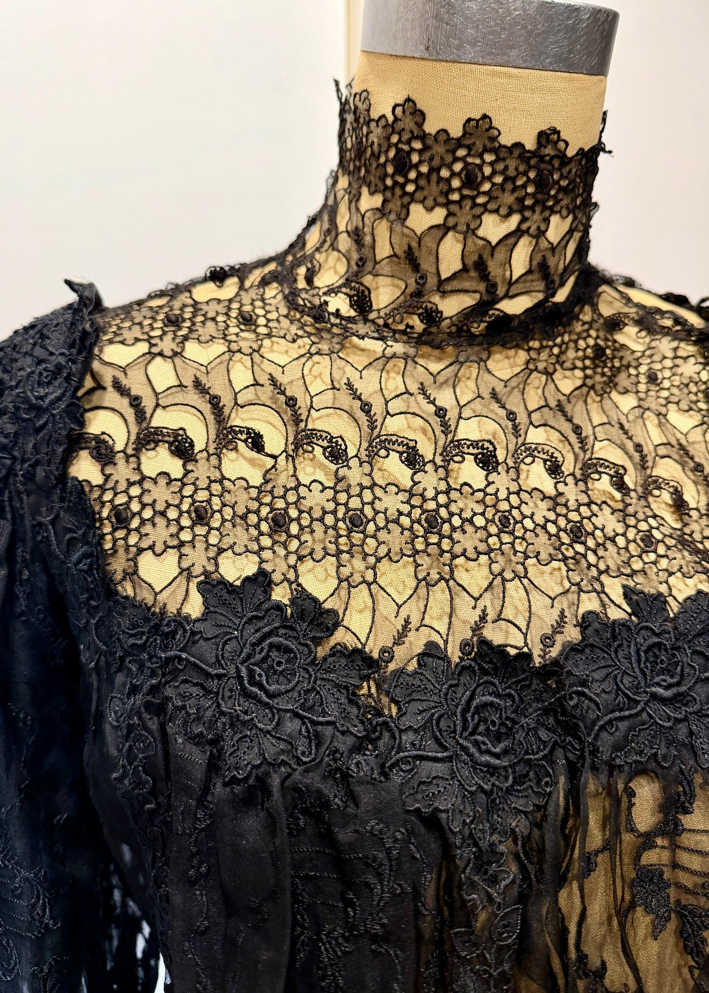 1890's Victorian mourning corset Black lace garment on a mannequin with a plain background