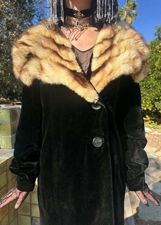 Person wearing a black coat with a fur collar outdoors