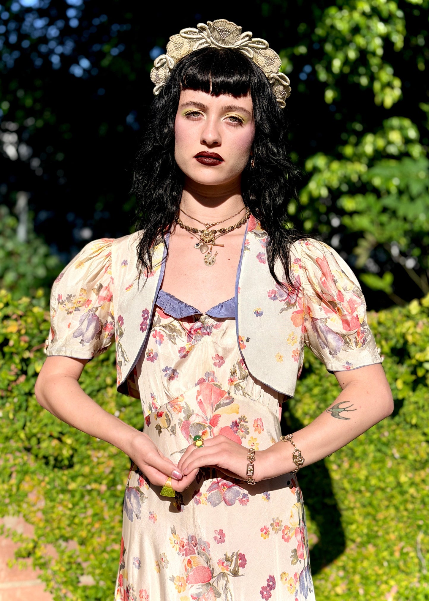 Woman in a floral  antique 1930s floral dress standing outdoors with greenery in the background