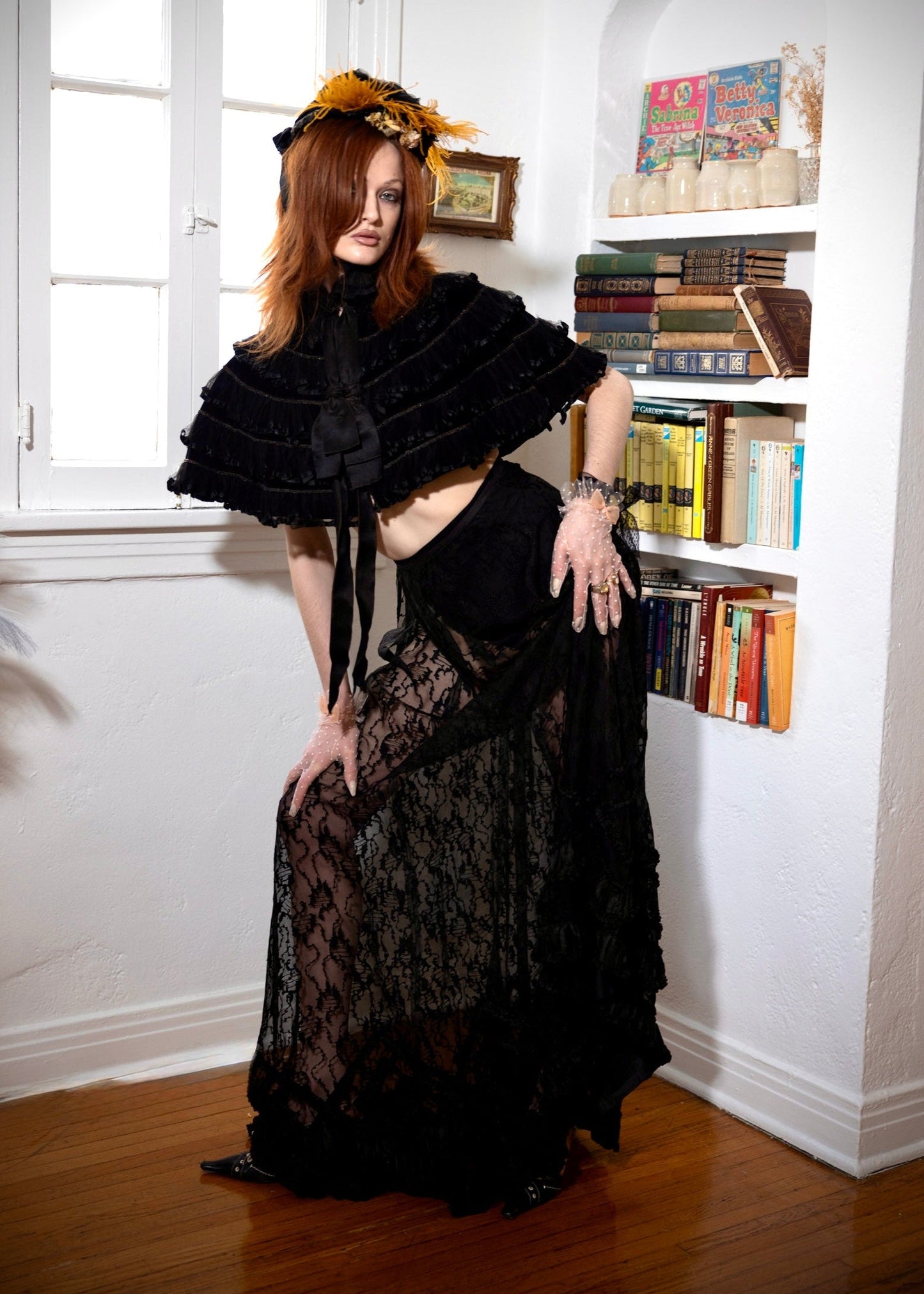 Woman in a black outfit standing in a room with a bookshelf.